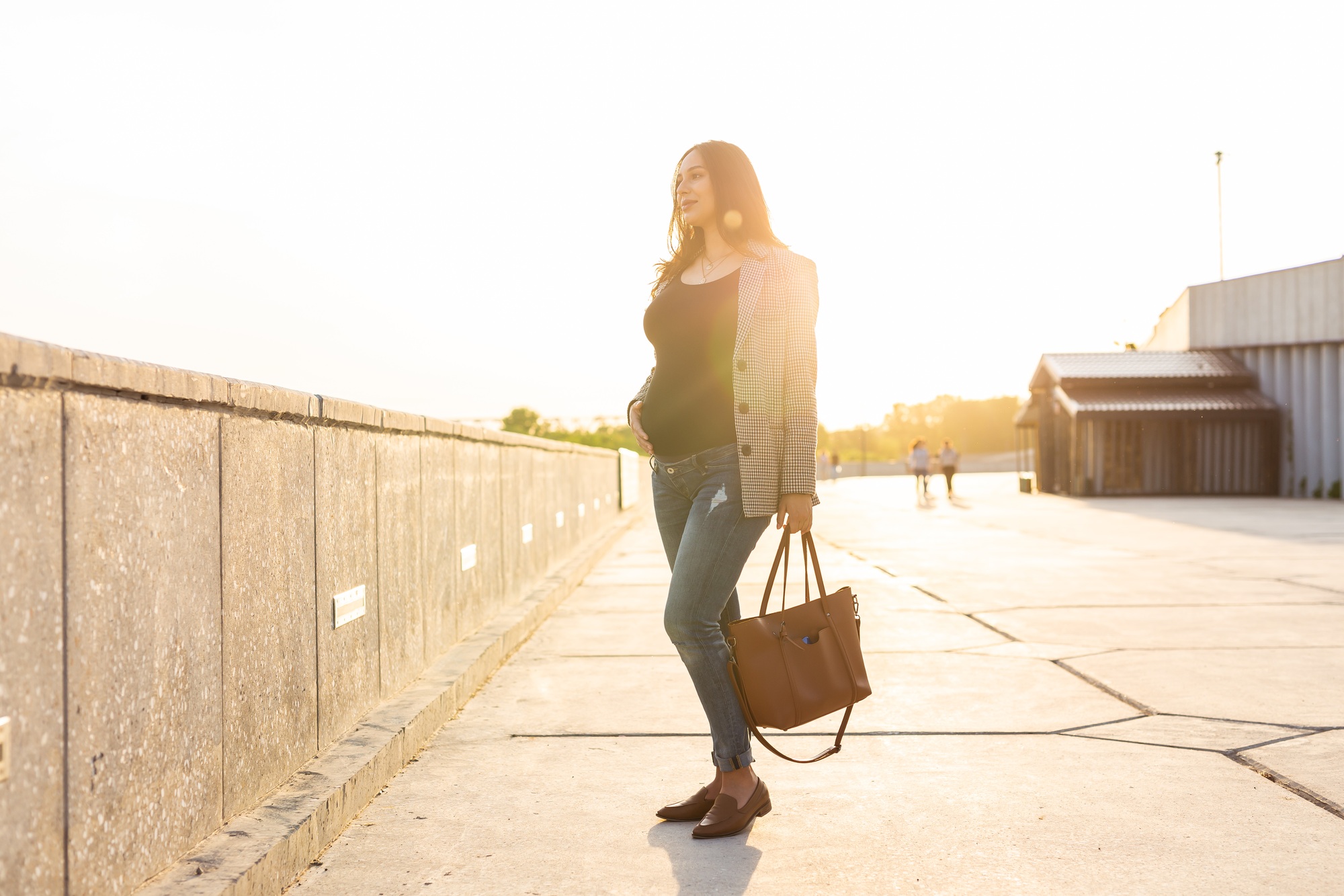 Active pregnancy concept. Young pregnant business woman or student sitting on the bench. Future mom
