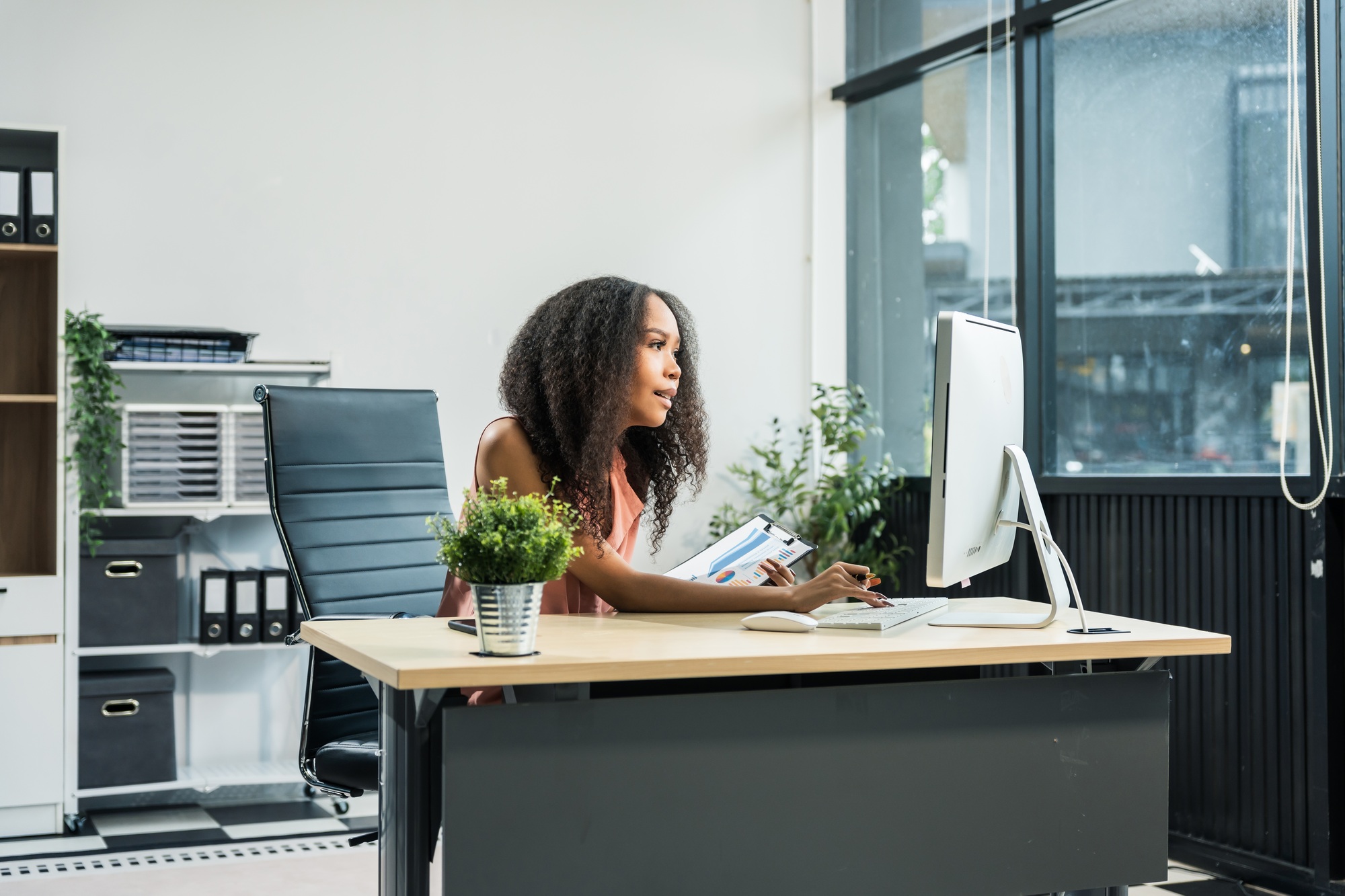 African American woman with afro at desk, managing finance, market research, investors for startup.
