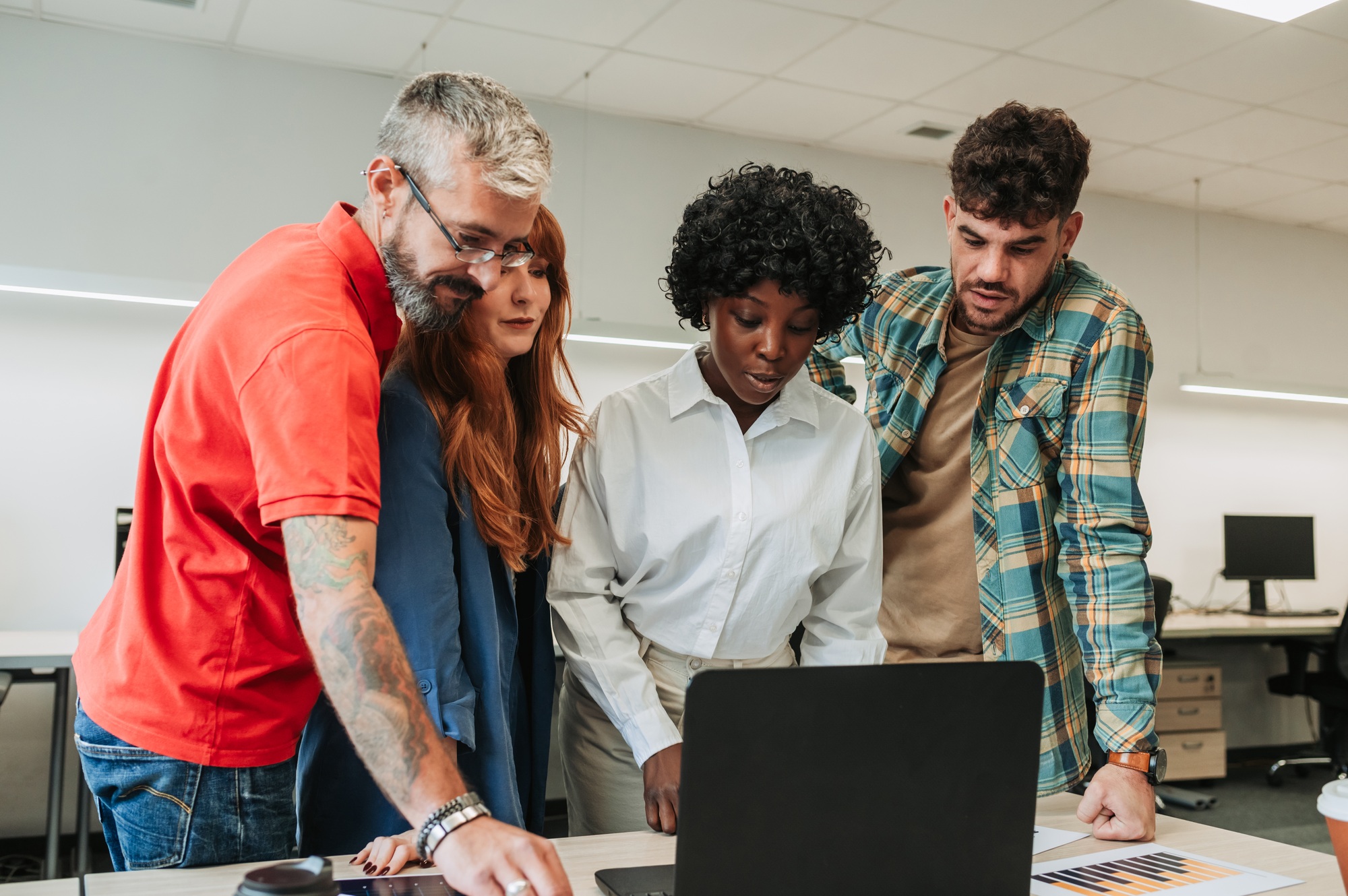 An interracial team is standing at the office and doing market research.