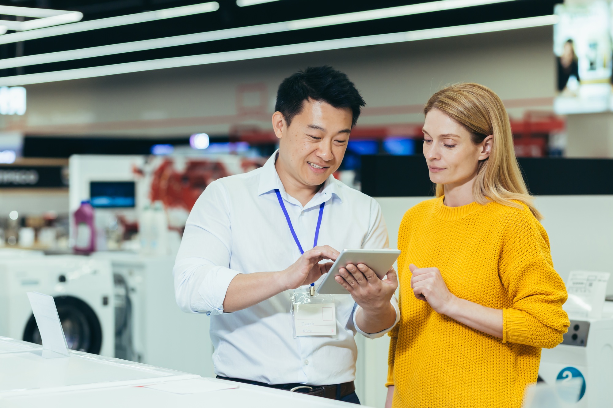 Asian consultant salesman in electronics and household appliances store, selling