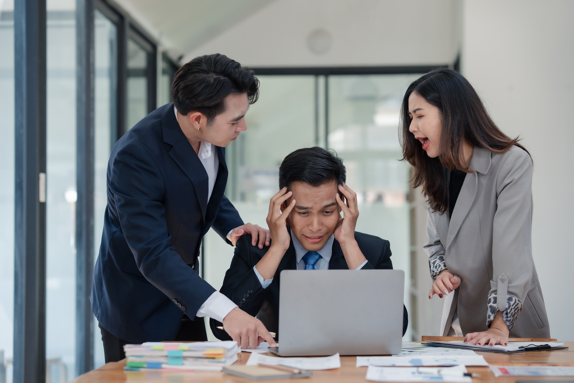Business team in office environment experiencing stress and conflict, with a frustrated man