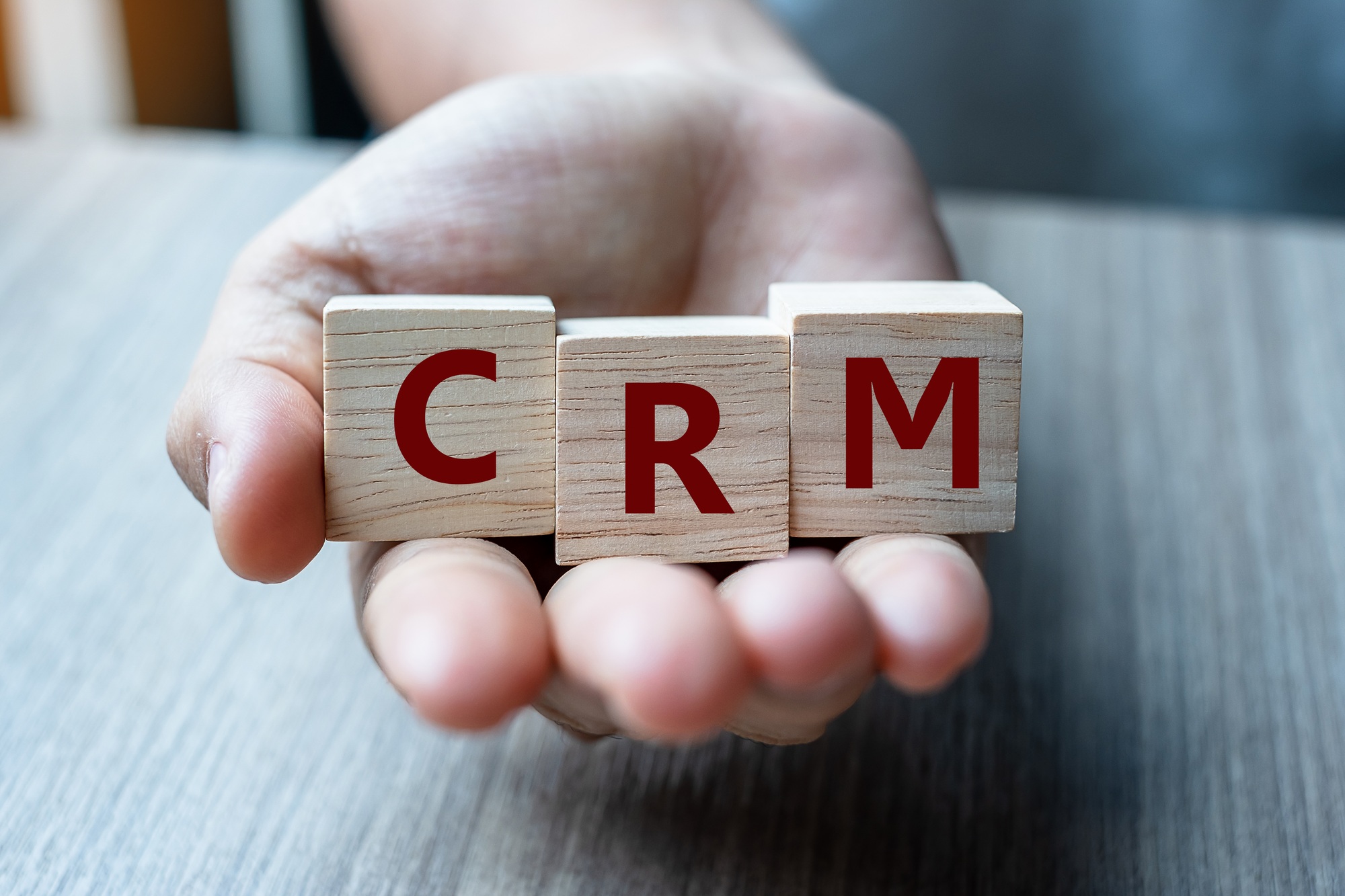 Business woman hand holding wooden cube with CRM text (Customer Relationship Management)