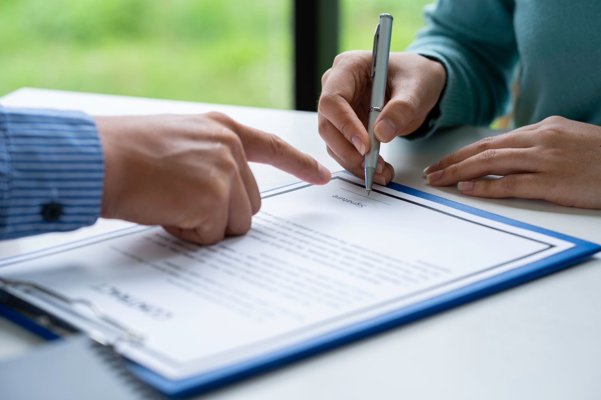 Businesswoman signing a document or application form in a folder, Businessmen hand's pointing where