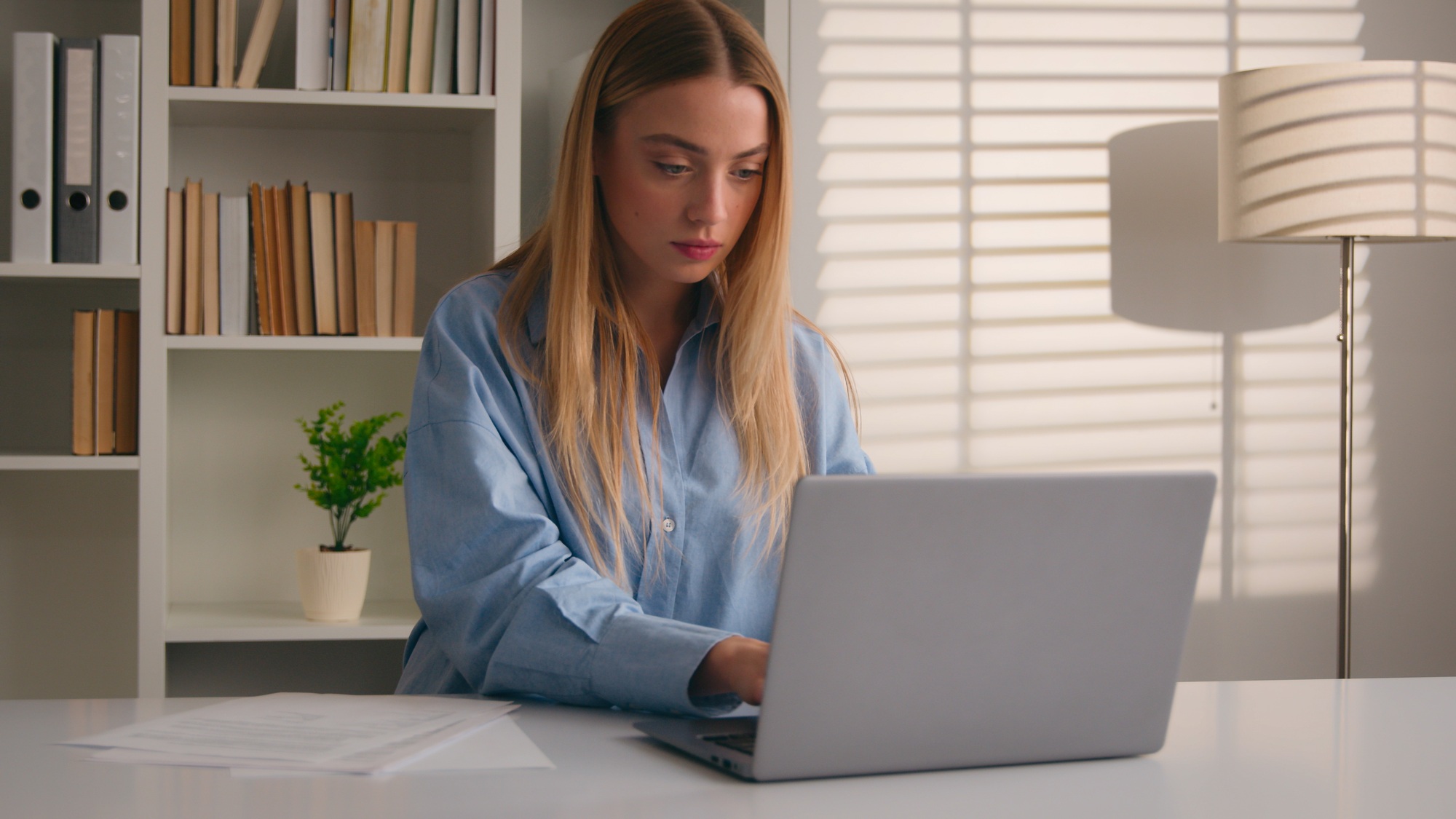 Caucasian businesswoman at office workplace work on laptop make market research analyze papers