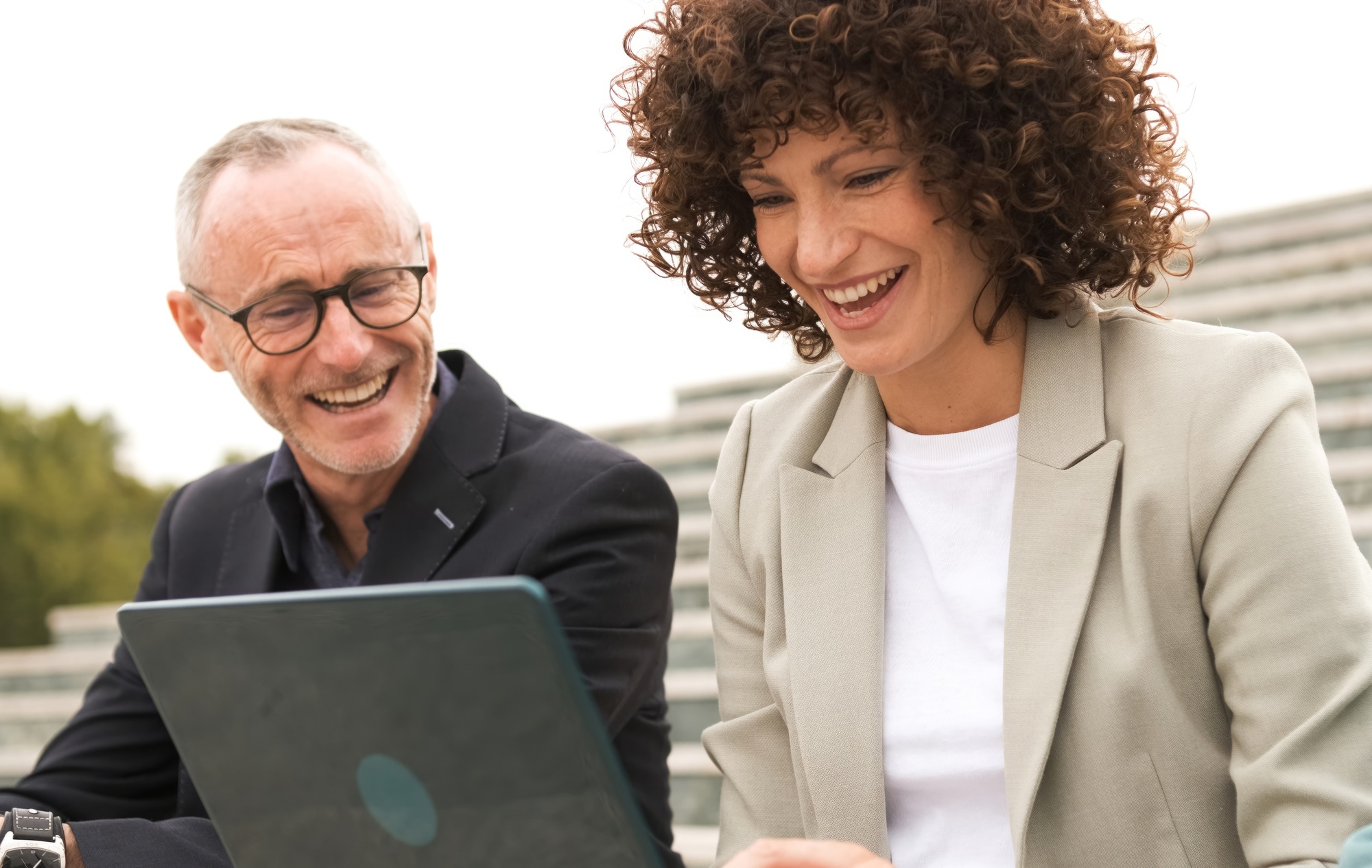 Cheerful business colleagues using netbook sitting on steps