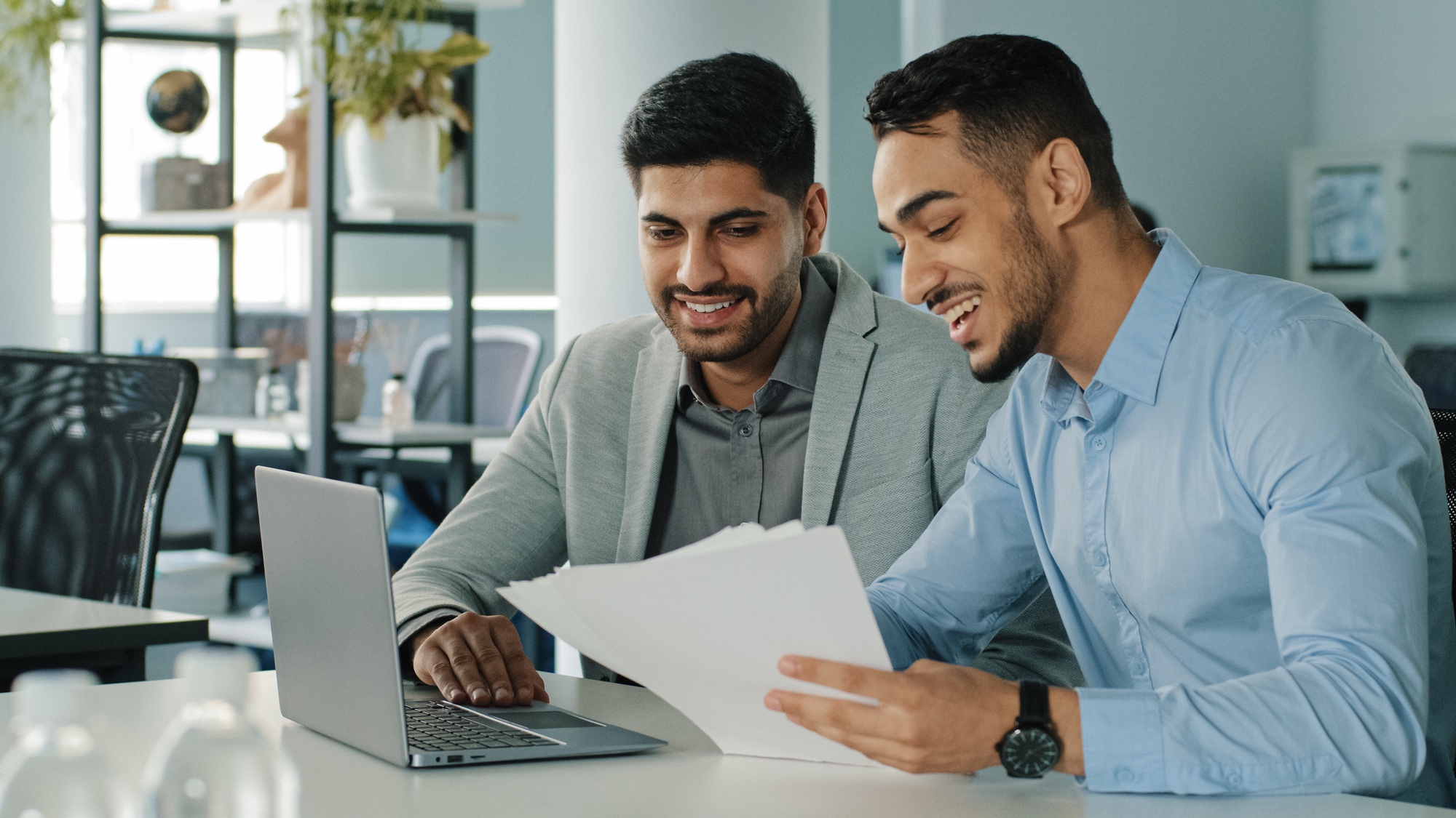 Cheerful positive friendly businessmen partners colleagues holding document contract looking at