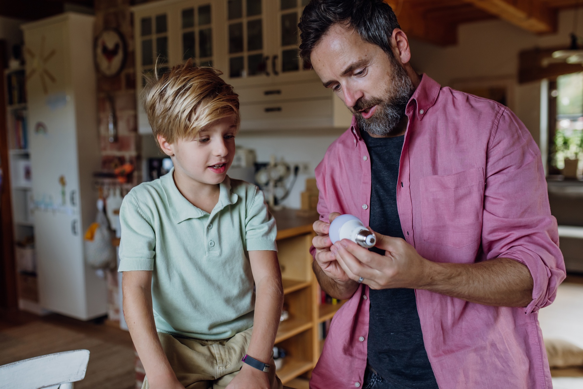 Father explaining led bubls to son, teaching him about energy efficiency, longevitiy and