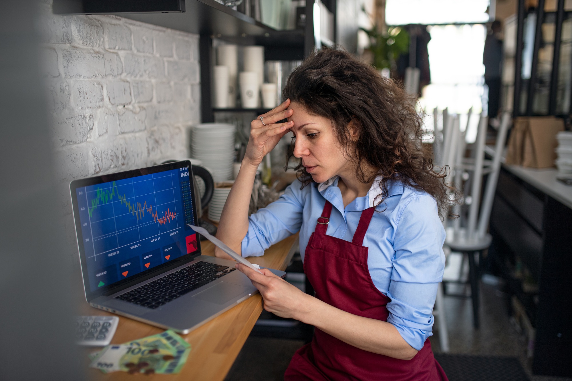 Frustrated coffee shop manager calculating figures in cafe, small business and new normal concept