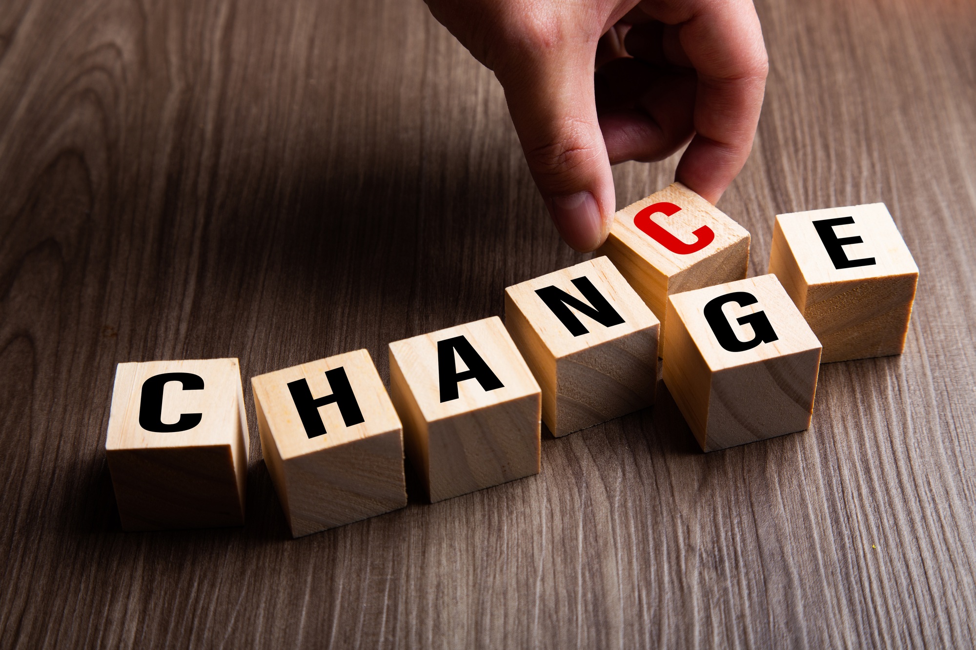 Hand changing wooden cube with word change to chance,.