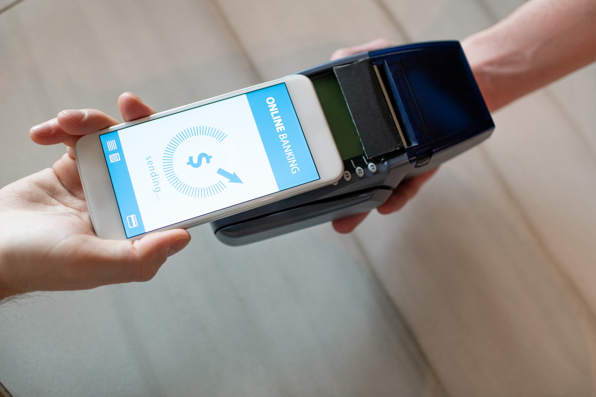 Hand of young man with smartphone paying by online banking in restaurant