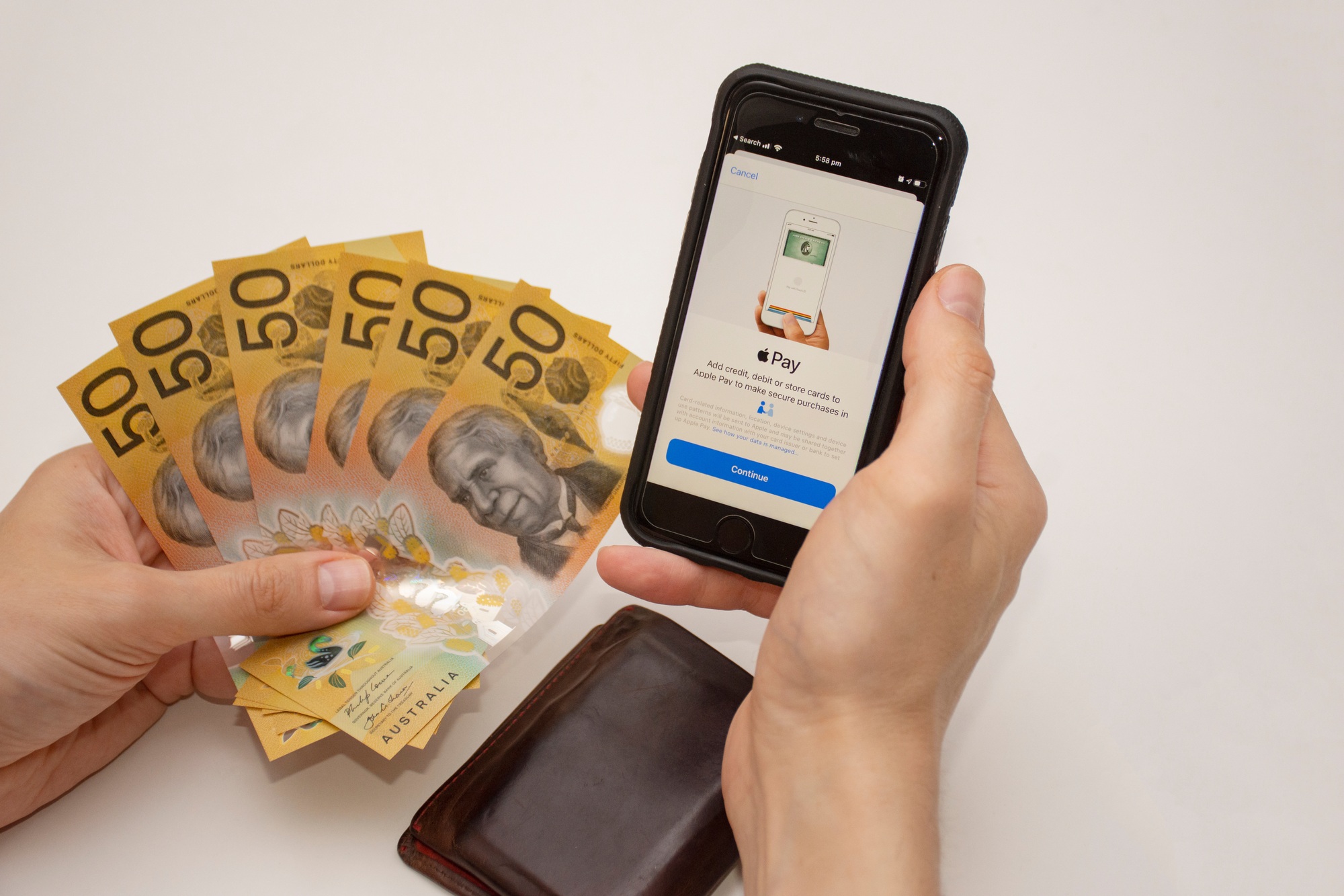 Hands holding a mobile phone with Apple Pay on it and US dollars. Contactless phone payment concept