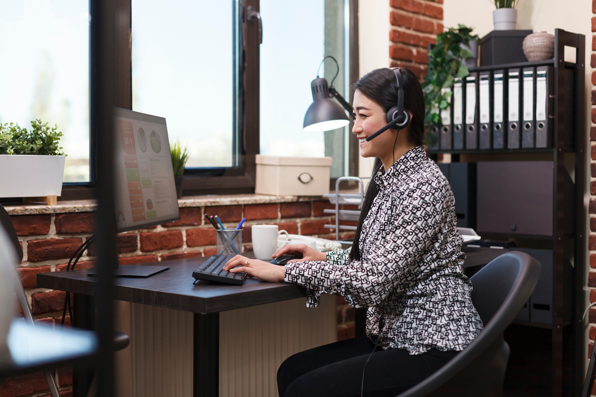 Happy asian sales agent with headset on call with potential product buyer