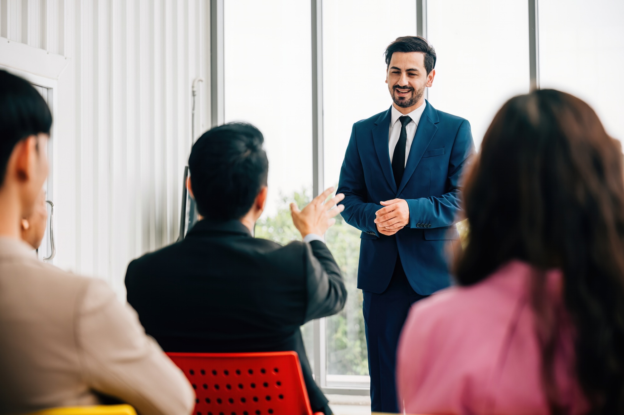 In a meeting room, business leaders present their insights, while a diverse audience of colleagues