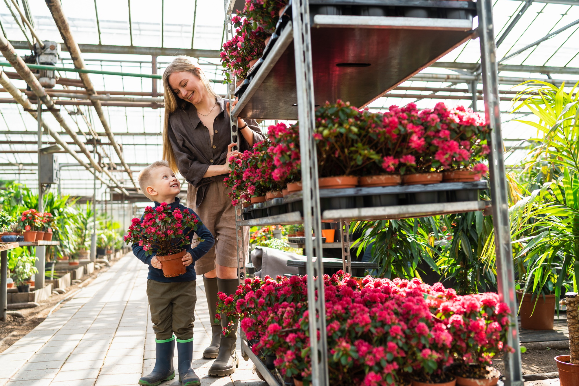 Little boy with a flower in a pot and his mom, a florist who pulls a cart with flowers