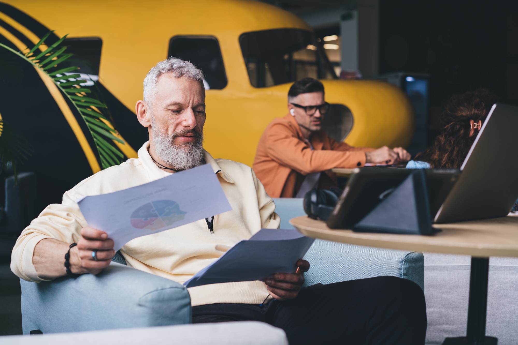 Mature male entrepreneur checking business statistics while creating report for startup project