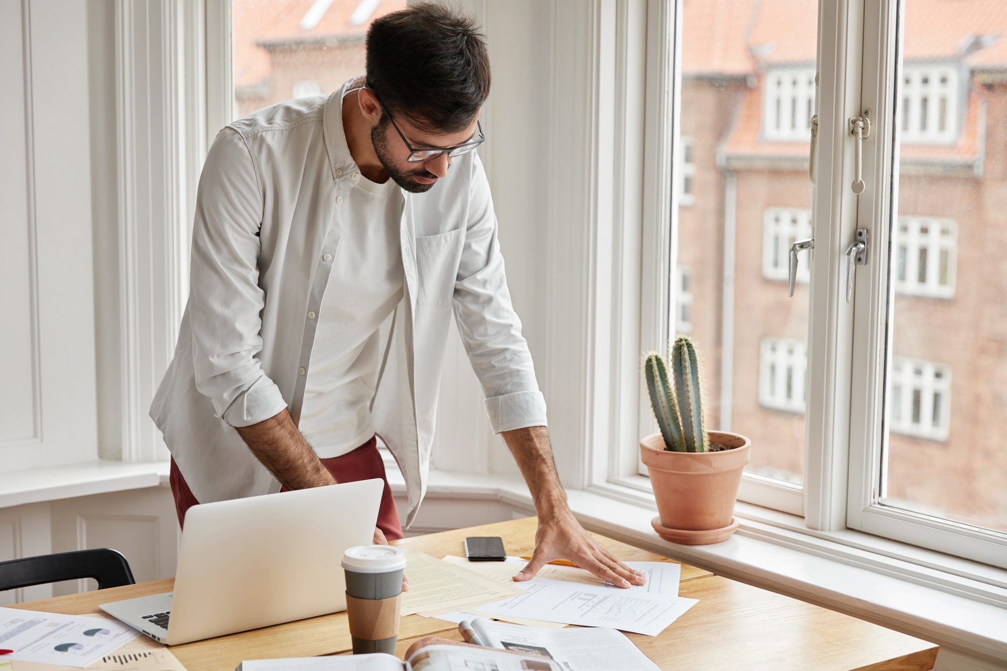 Paper work and business concept. Successful businessman works in home cabinet, studies graphics and