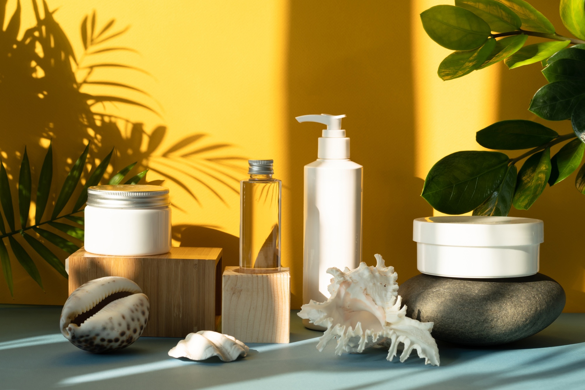 Summer shadows of tropical palm trees on a yellow background. Simple examples of cosmetics and skin