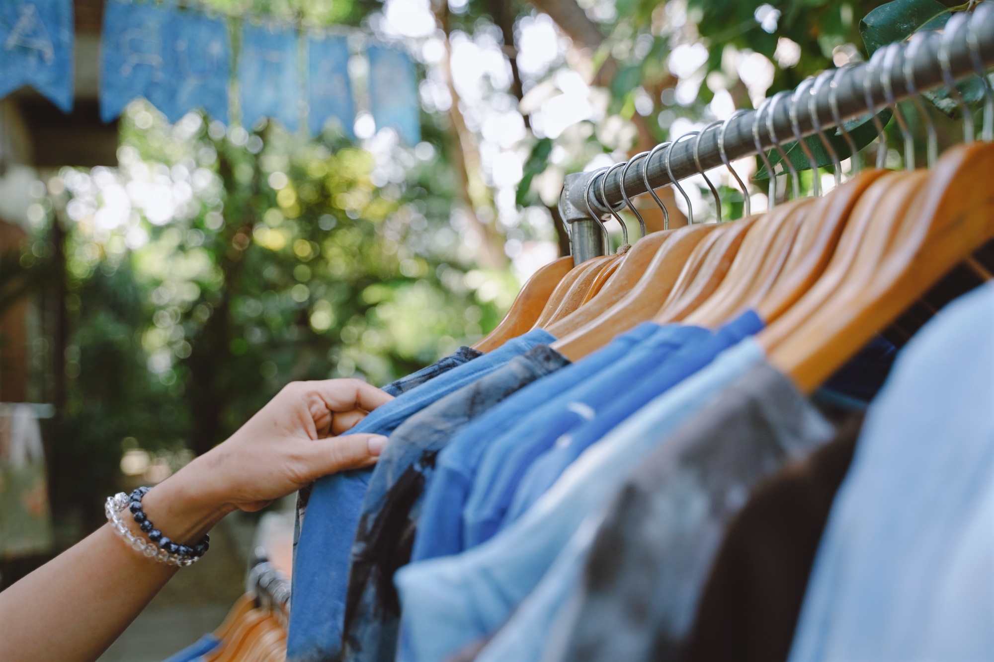 Woman hand choosing tshirt in outdoor booth store in the market