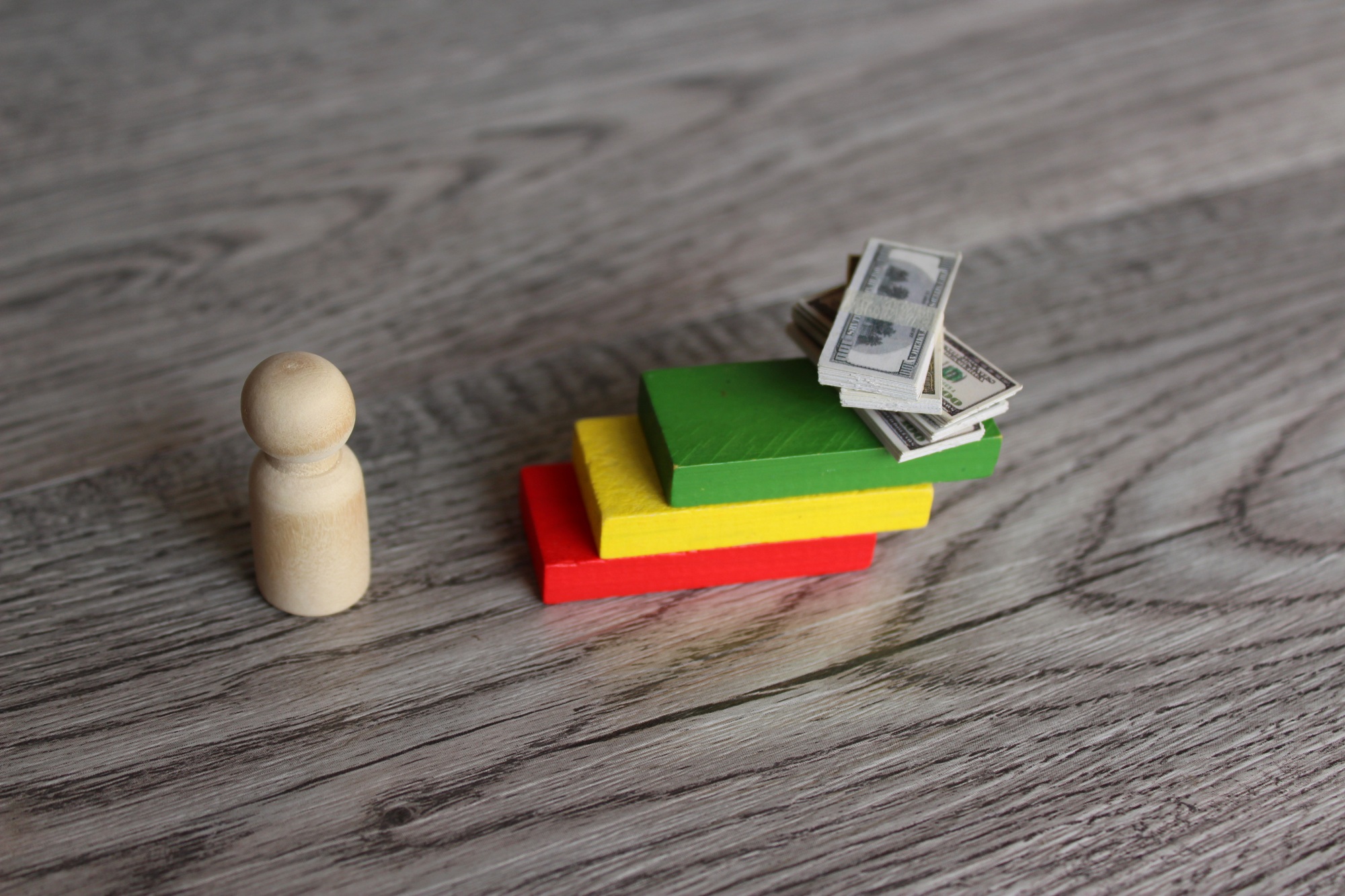 Wooden doll and stack of money on top of staircase.
