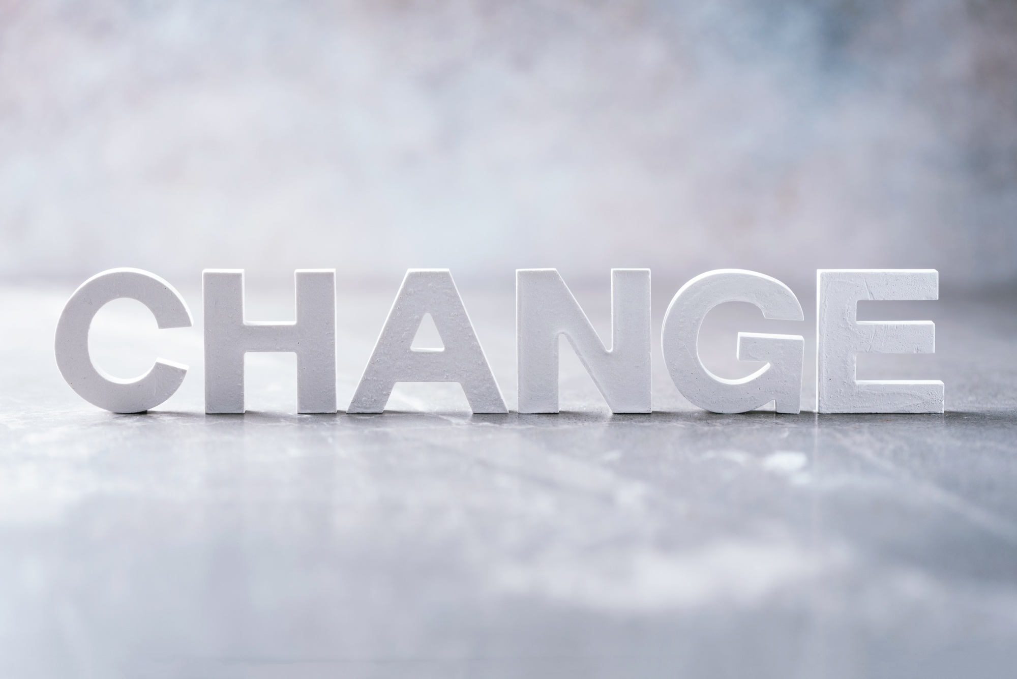 Word change word made with cement letters on grey marble background. Copy space. Concept