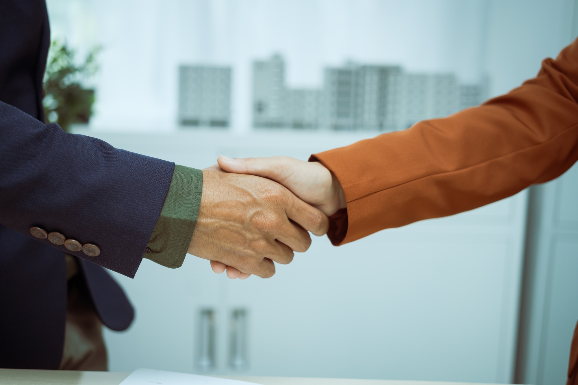 A businessman shakes hands with customer in the sales office after agreeing sign contract to buy