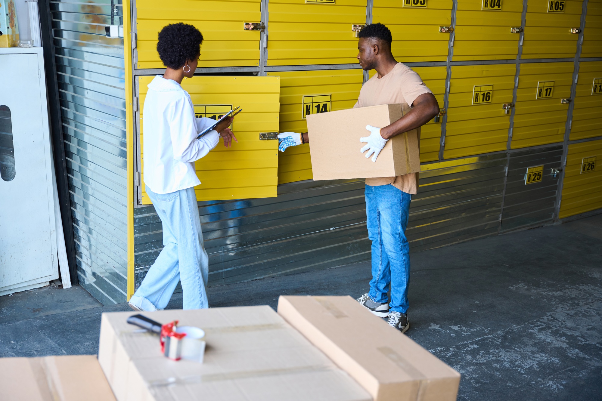African American guy loads a cardboard box into storage unit