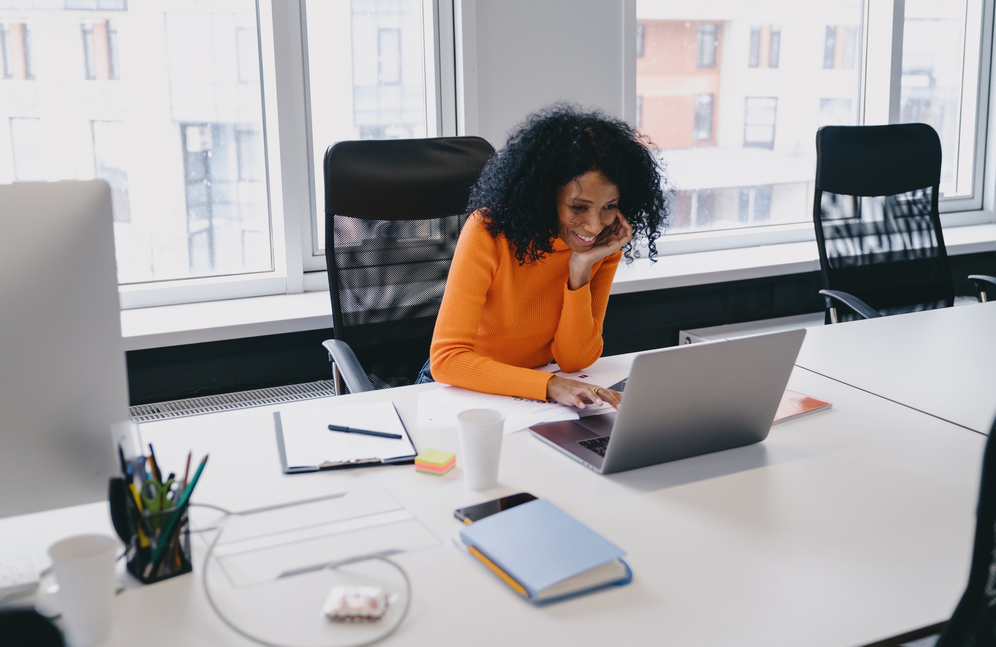 African American marketing manager in her 30s smiling while analyzing consumer data on her laptop in