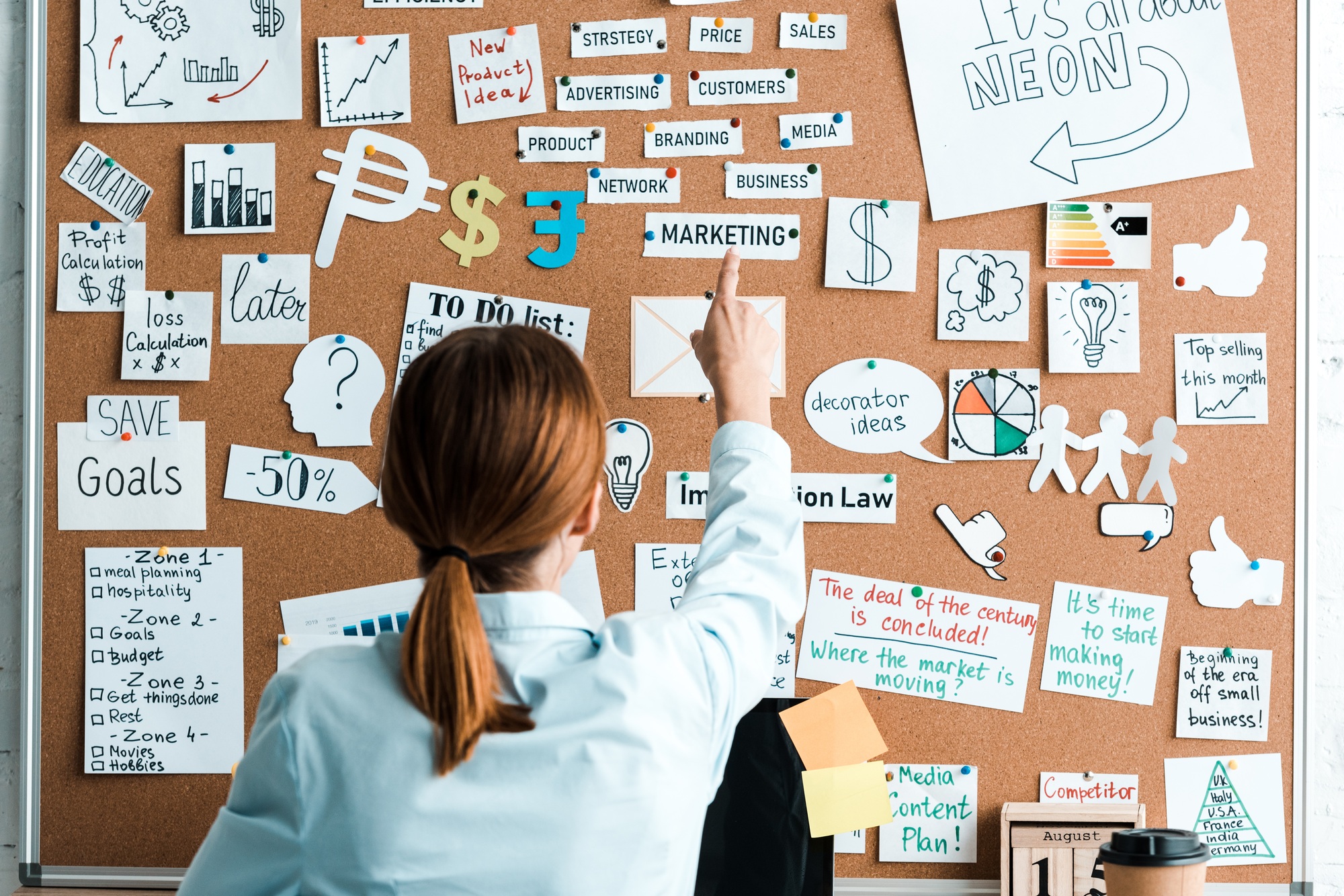 back view of businesswoman pointing with finger at marketing lettering on notice board