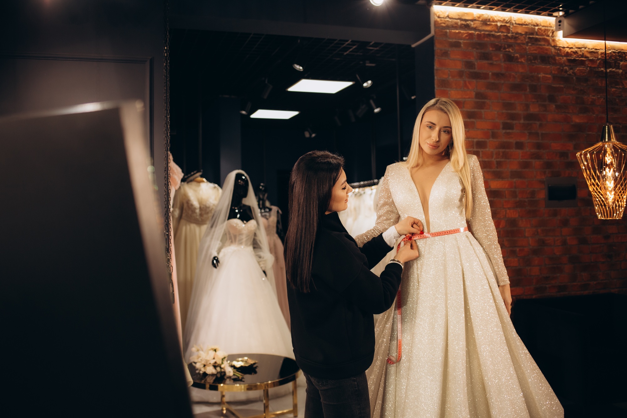 Beautiful bride getting dressed by her best friend in her wedding day and choosing a wedding dress