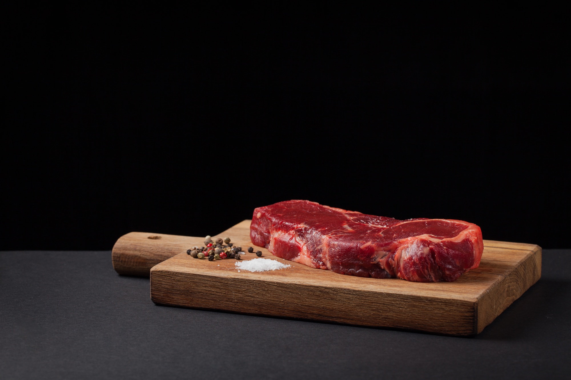 Beef steak on the wood black background with free space for text design or logotype menu restaurant