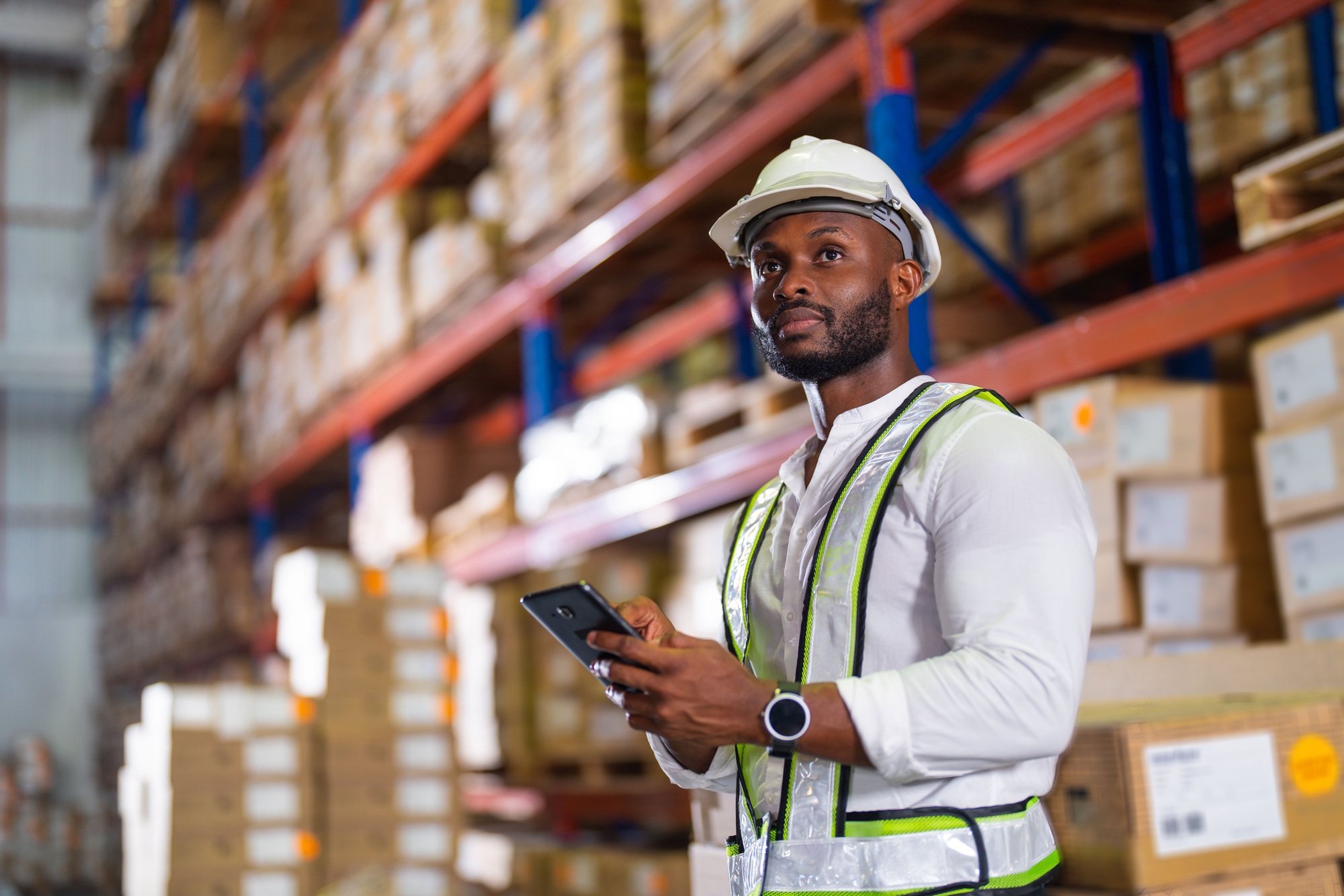 Black warehouse worker checking the delivery status of the package with a tablet