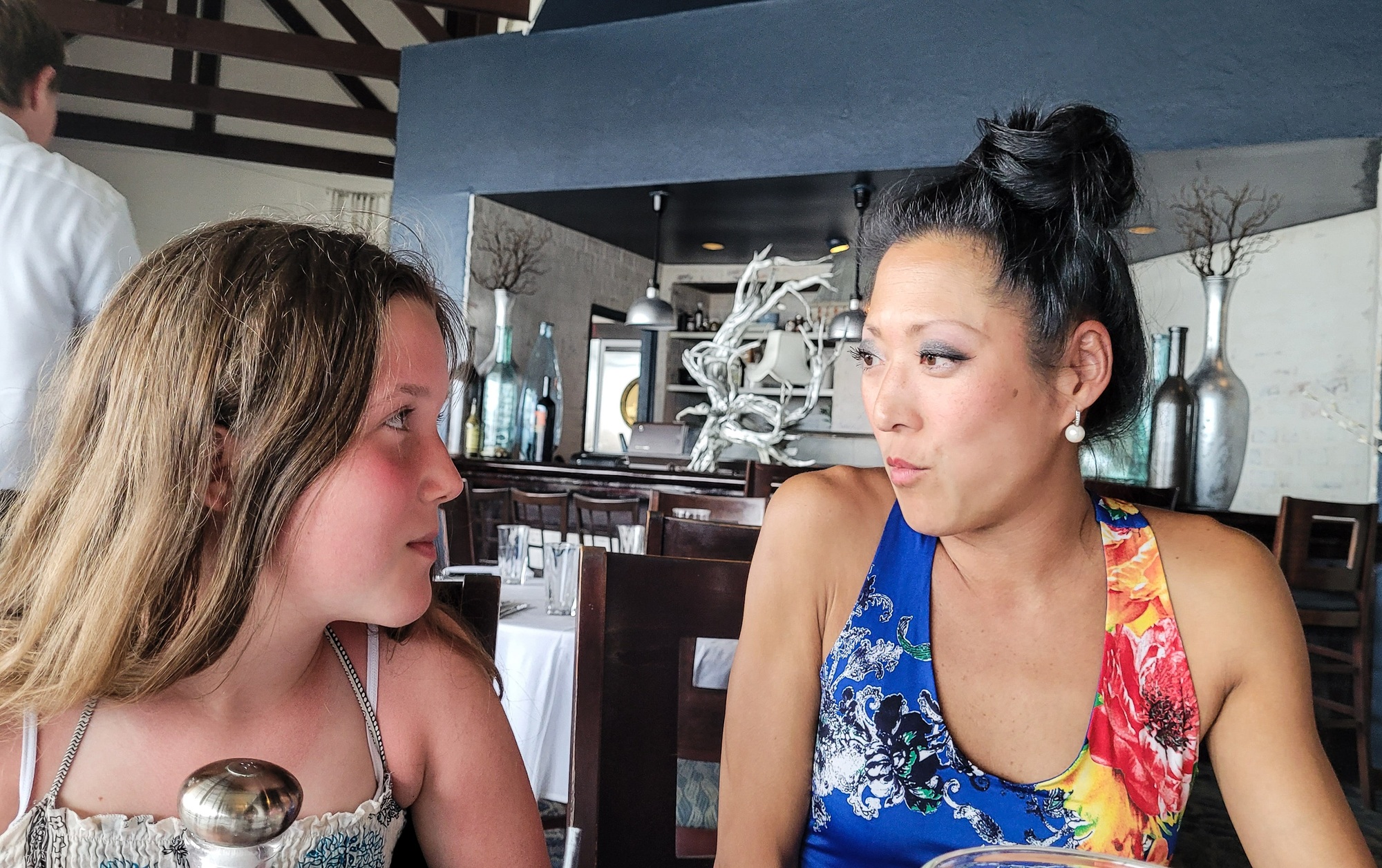 Diversified generation x talking to generation z stepdaughter in restaurant with faces and emotions.