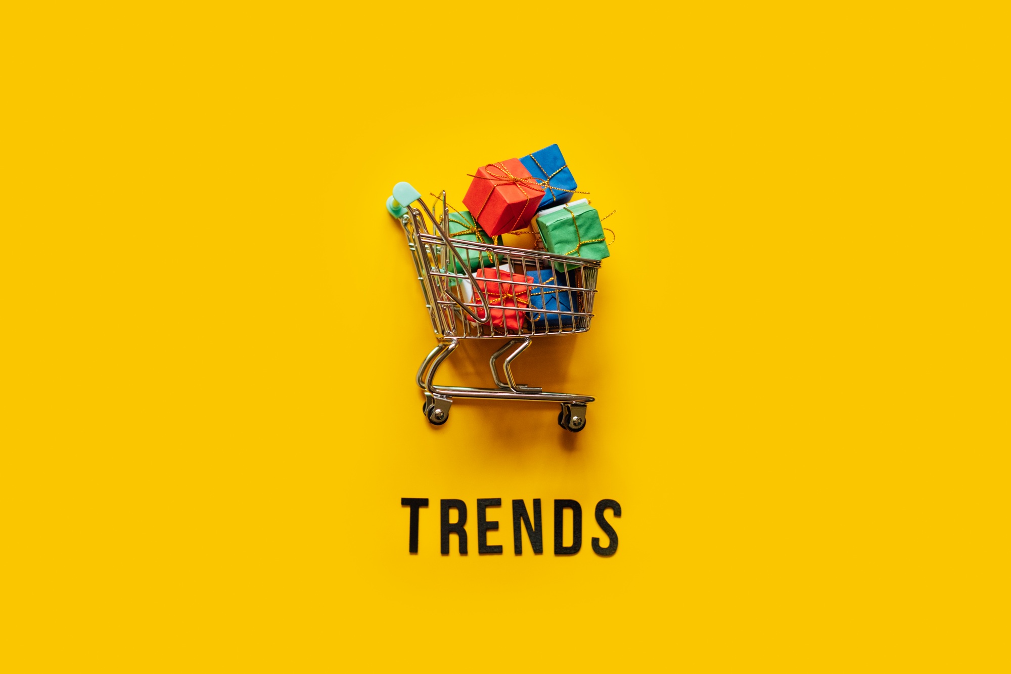 Ecommerce Retail Shopping trends concept. Word Trends and mini shopping cart with box on yellow