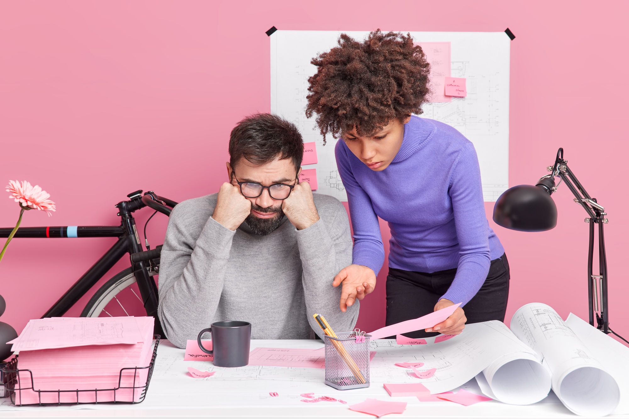 Frustrated diverse woman and man focused at sketches displeased to fing some drawbacks in project tr