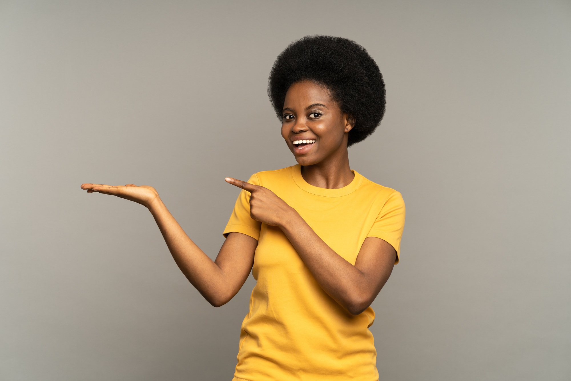 Happy excited female point finger to open palm with empty space for product placement happy smiling