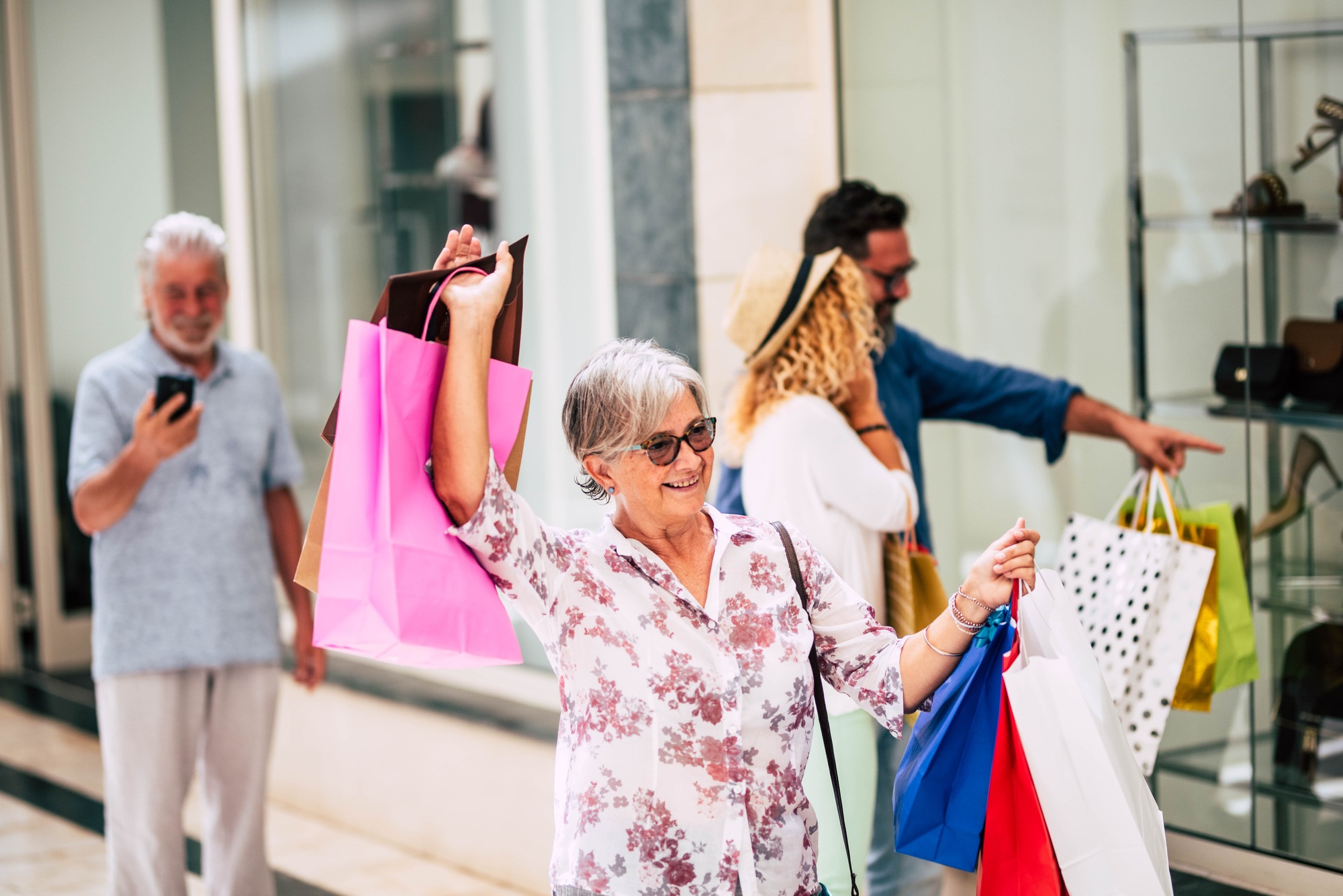 happy senior or mature woman doing shopping and holding shopping bags