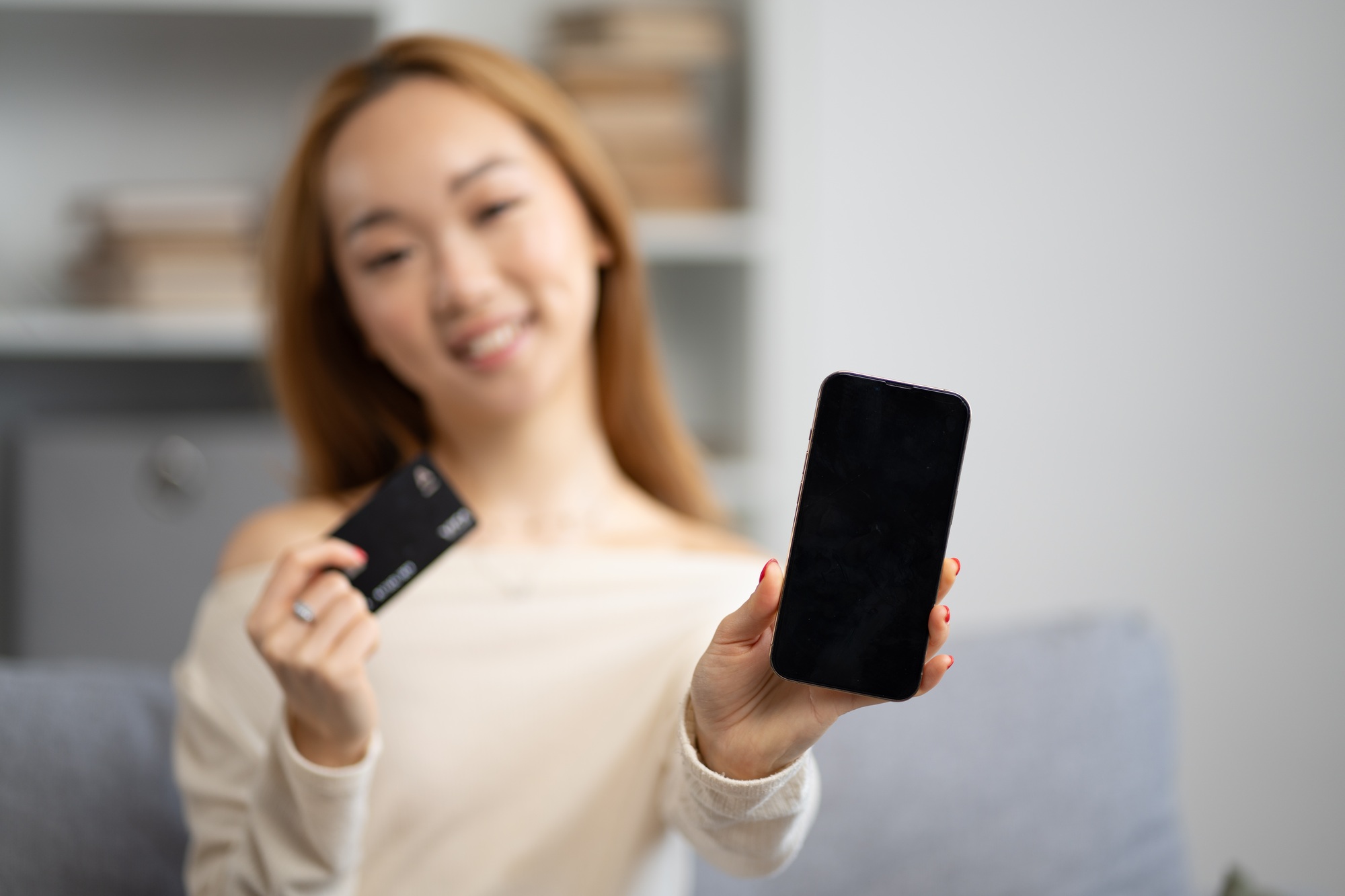 Happy Young Woman Showing Smartphone And Credit Card At Home