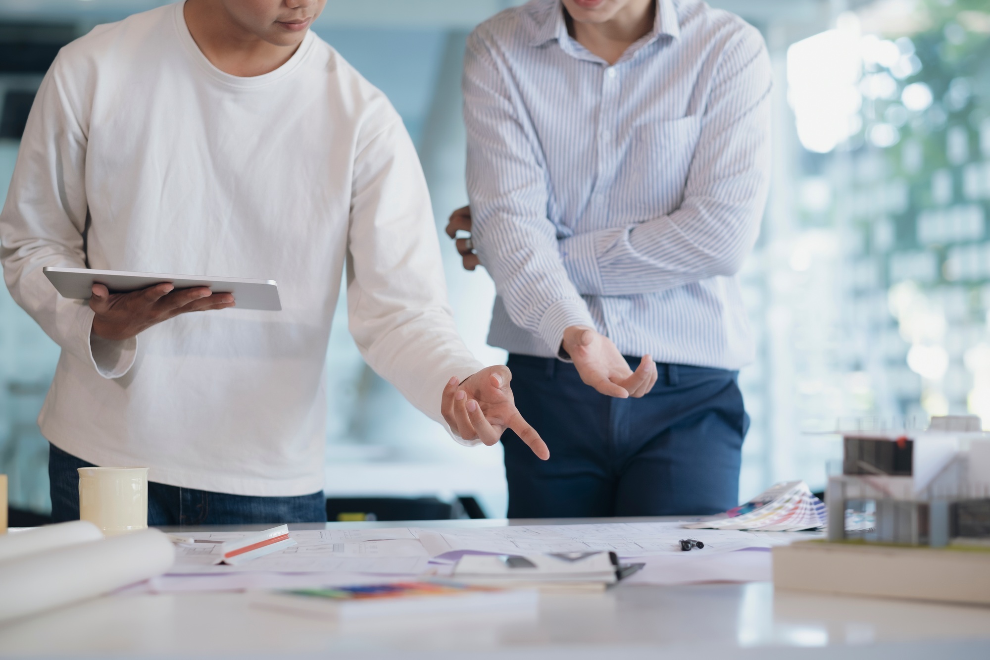 Interior designer discussing blueprint with male coworker in office.