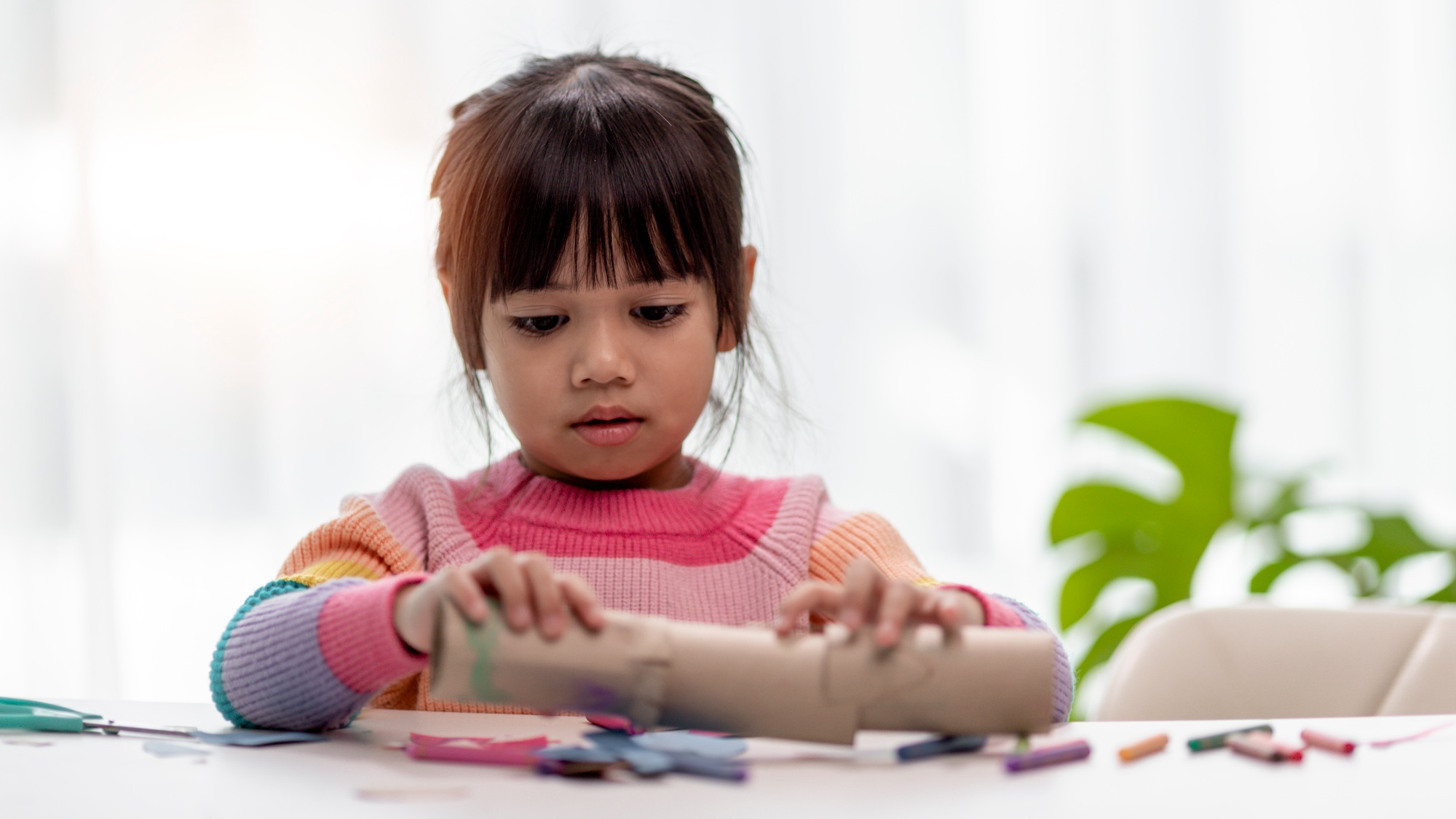 Little Asian girls are making tissue paper core binoculars. Reuse waste products. Idea