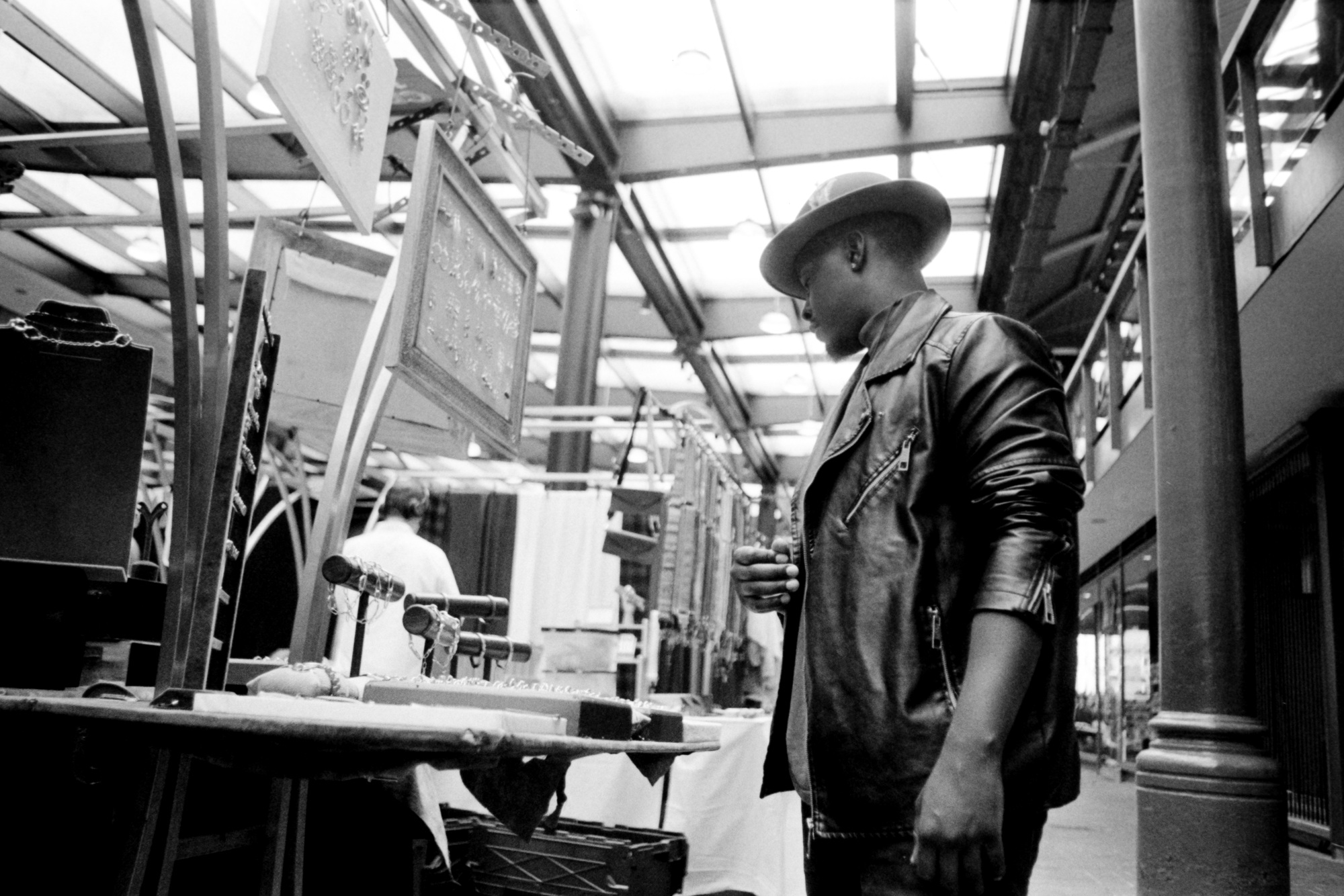 Man in a street market looking at jewelry in a black and white image.
