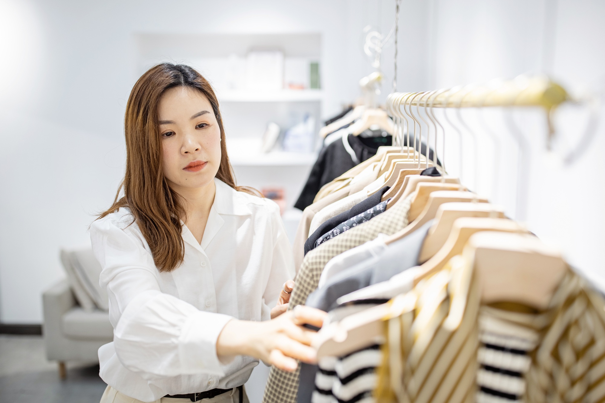 portrait of happy chinese female entrepreneur working in her modern store with womenswear clothes