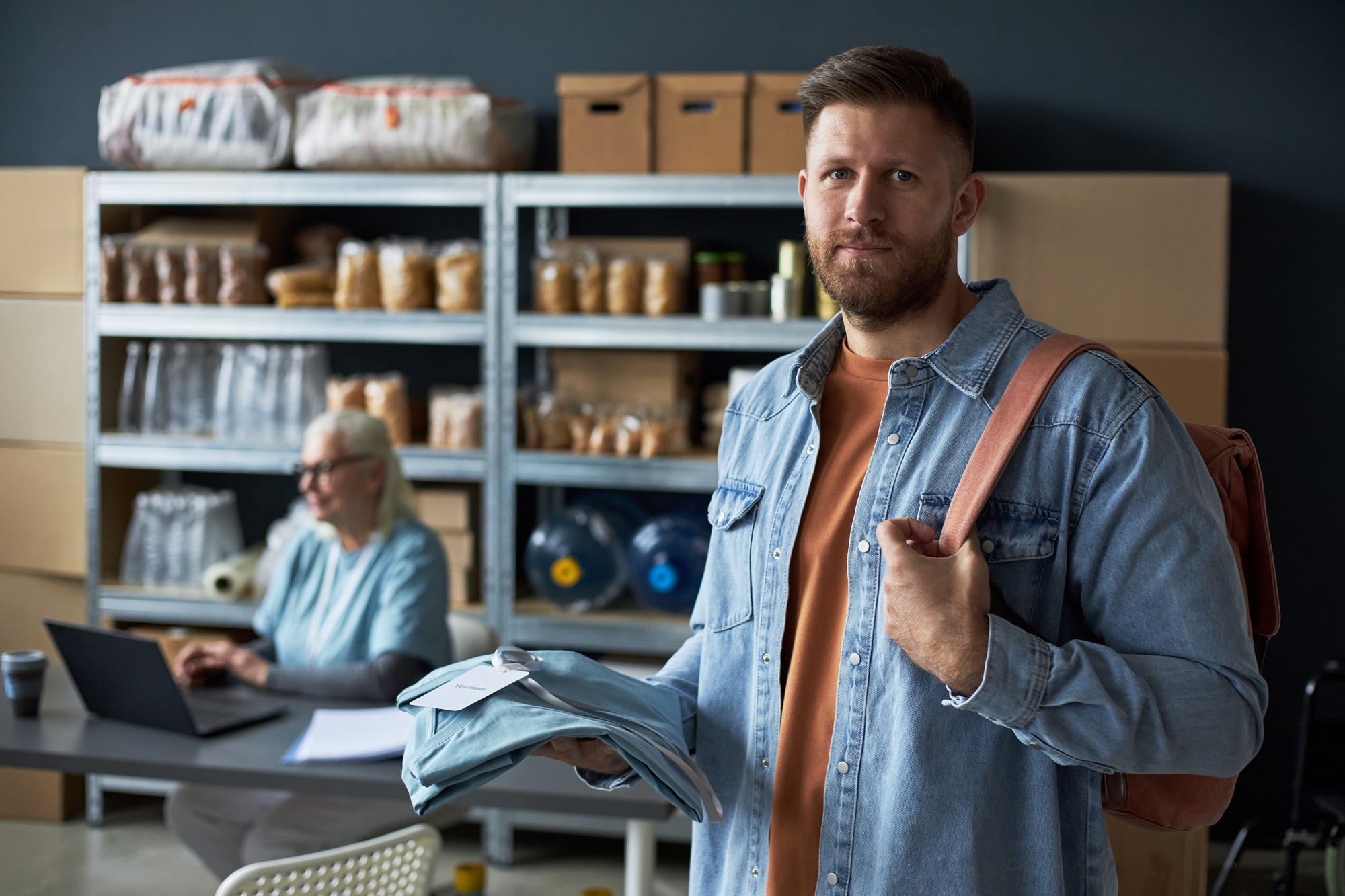 Portrait of Man Holding Clothes in Storage Facility