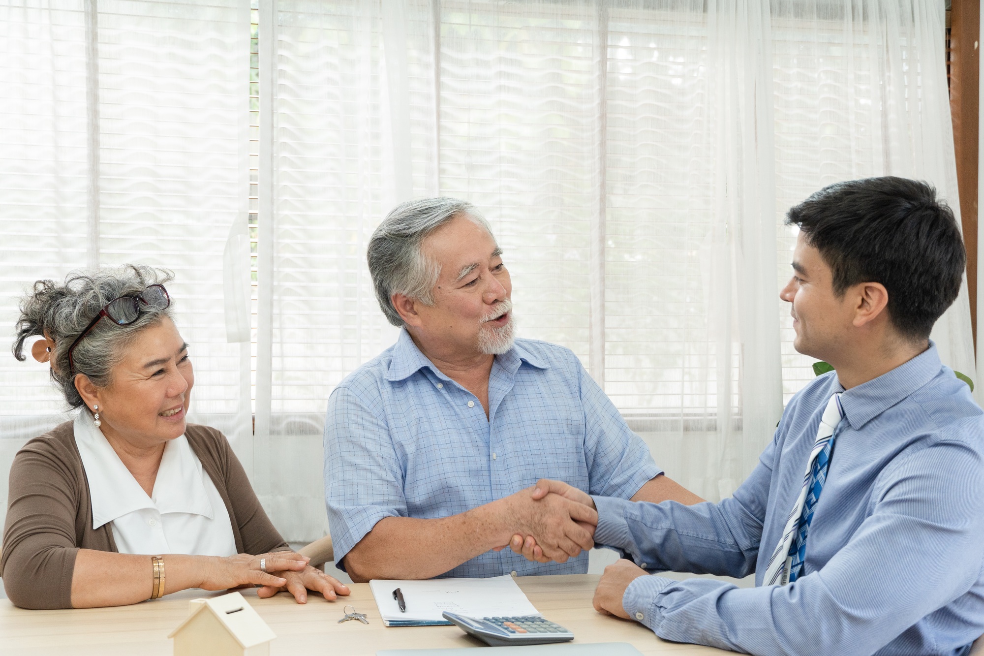 Retired couple making purchase and handshake with sales agent