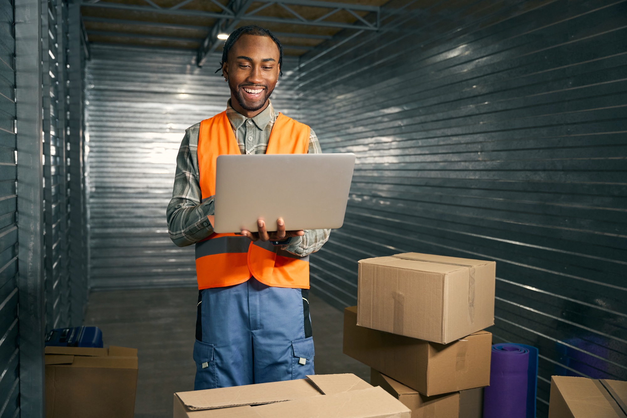 Smiling employee using laptop in storage unit