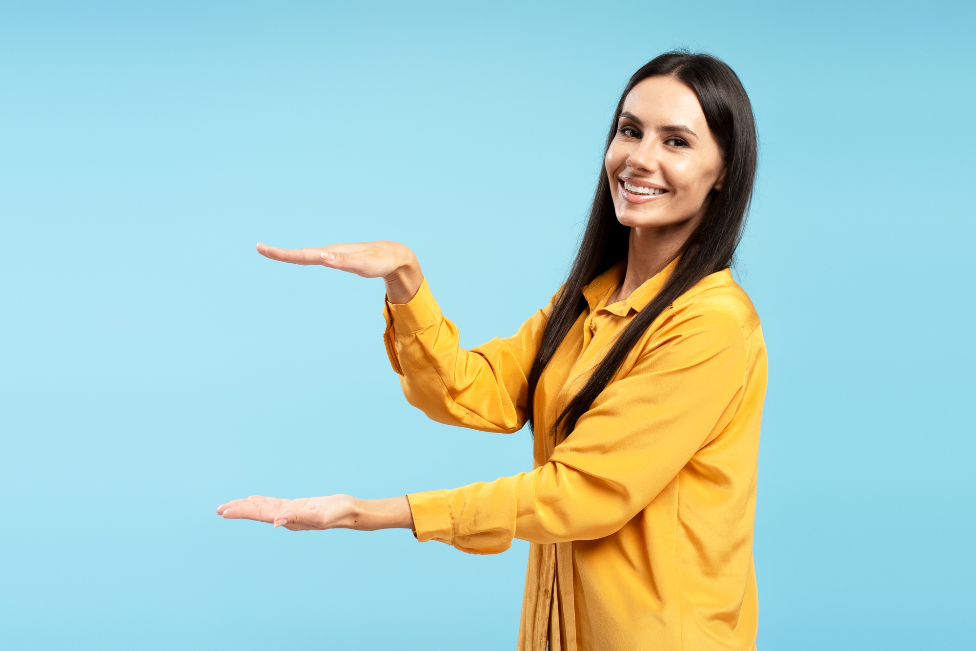 Smiling Latin woman showing space for product placement on blue background