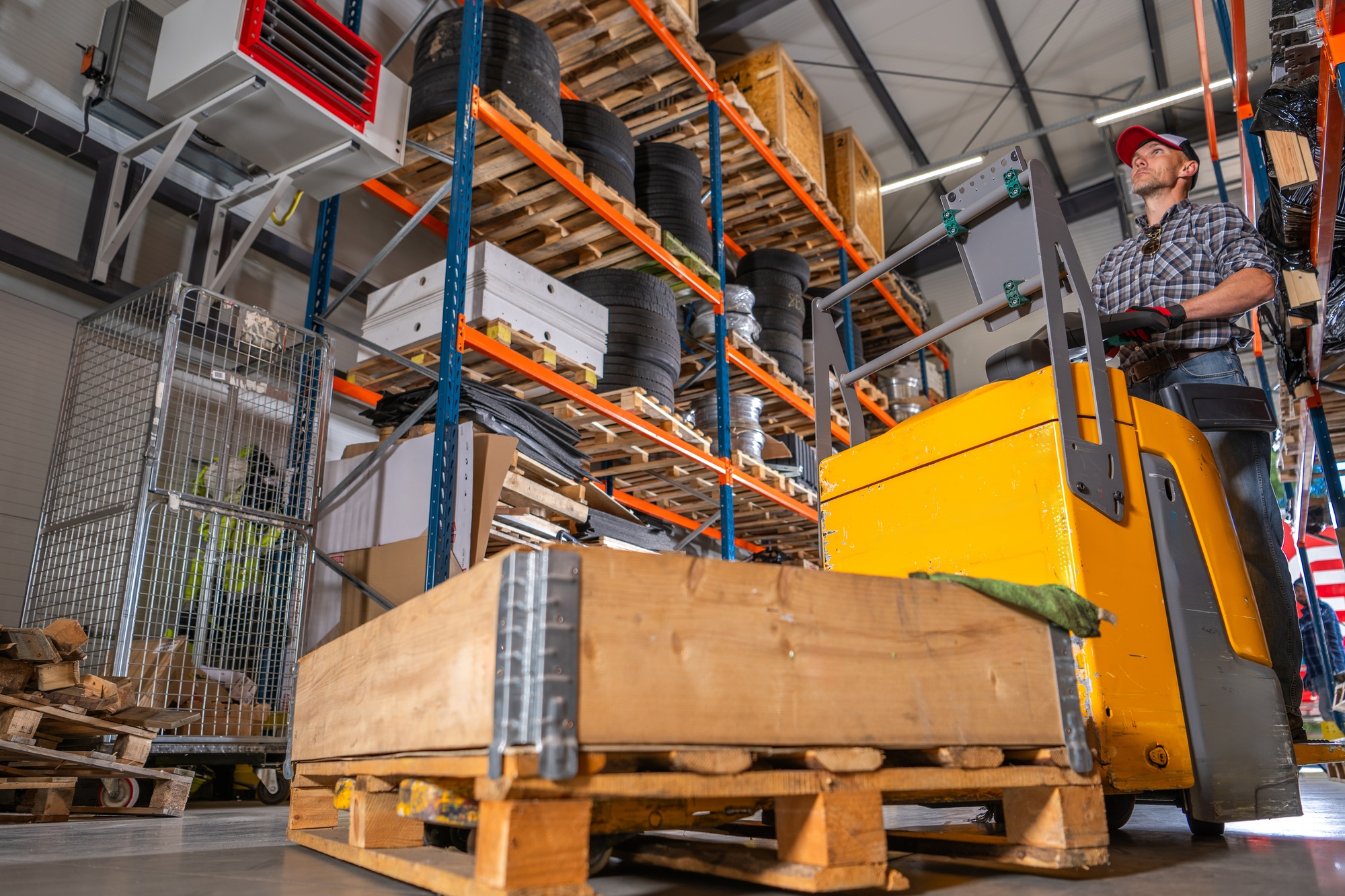 Warehouse Worker Operating a Pallet Truck in a Busy Storage Facility During Work Hours