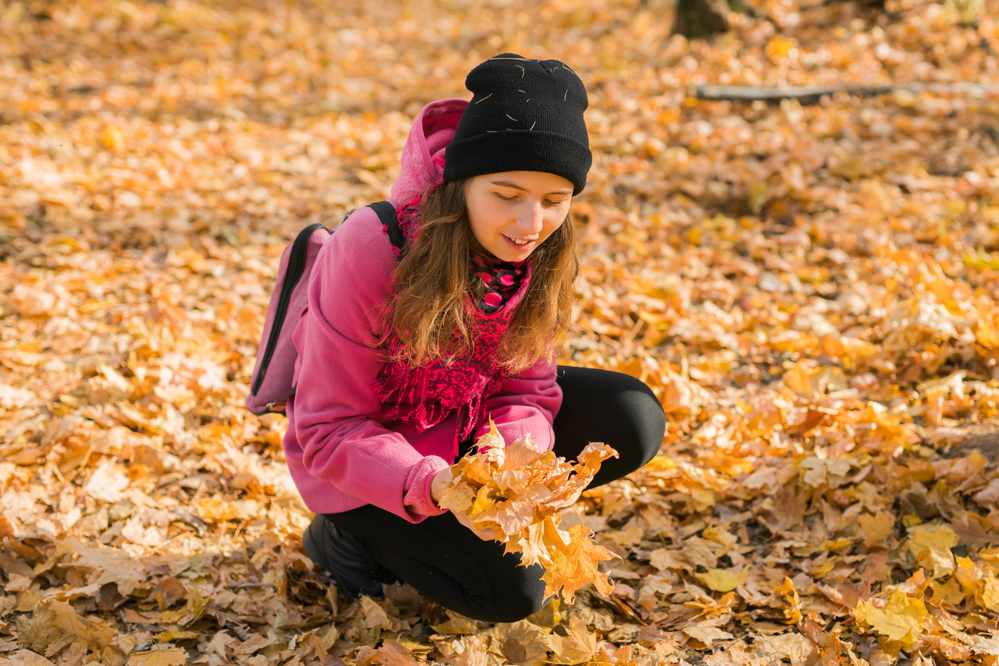 Young woman in a hat collects autumn leaves. Fall season concept. Generation Z and gen z youth