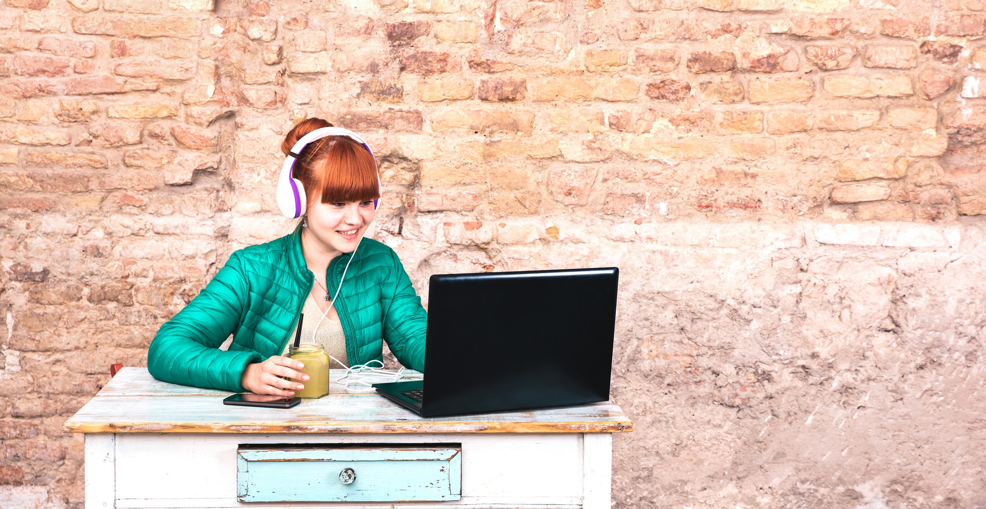 Young woman with headphones using laptop at house office