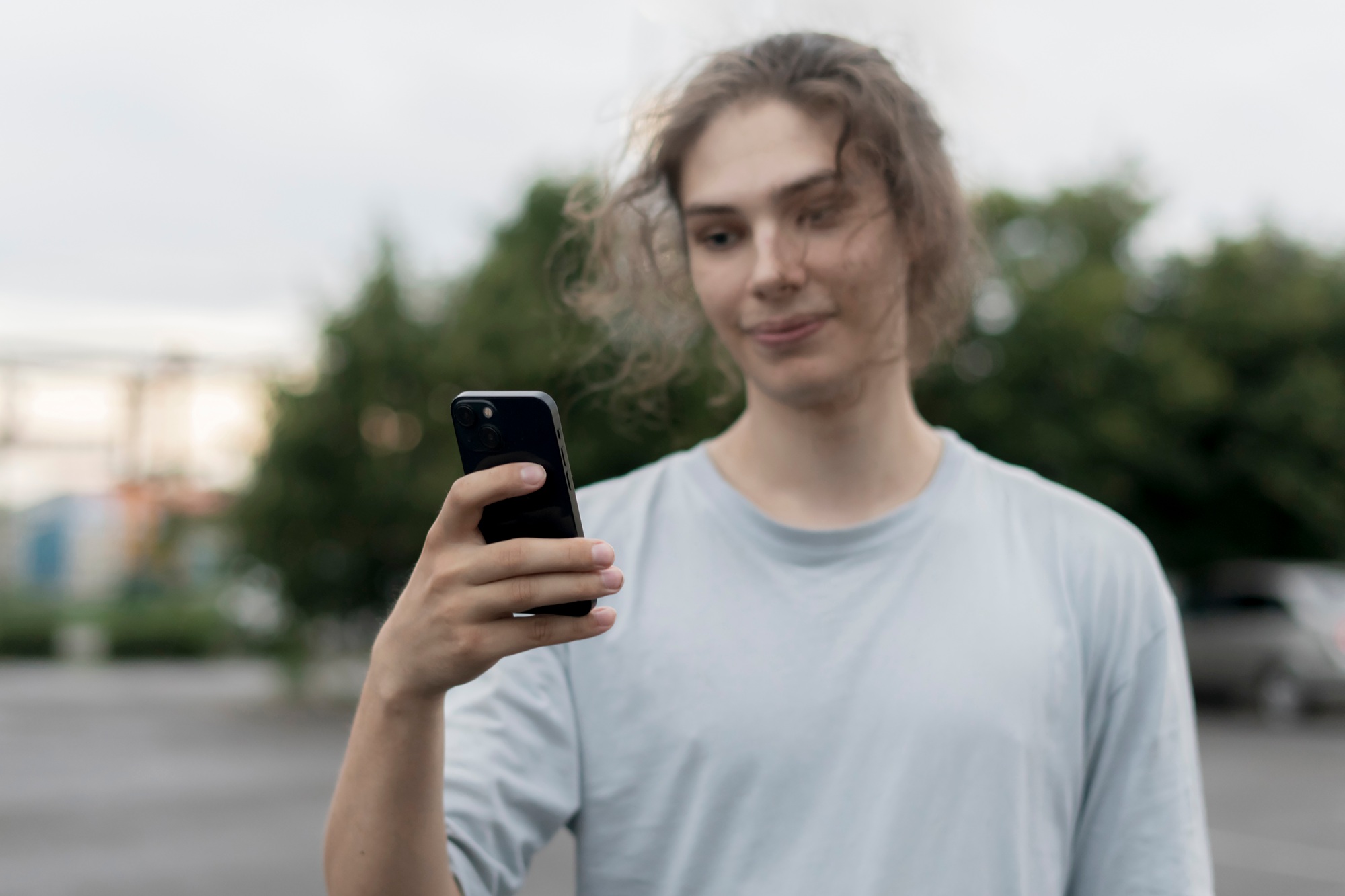 a person in the online social media platform; Holding Cell Phone, with Smartphone Outdoors