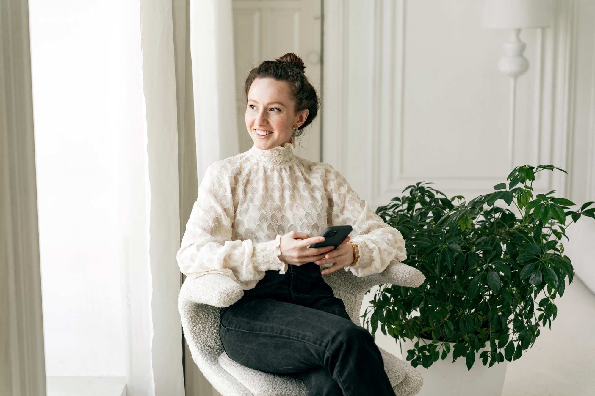 A young freelance woman in a white shirt in the office, using the phone.